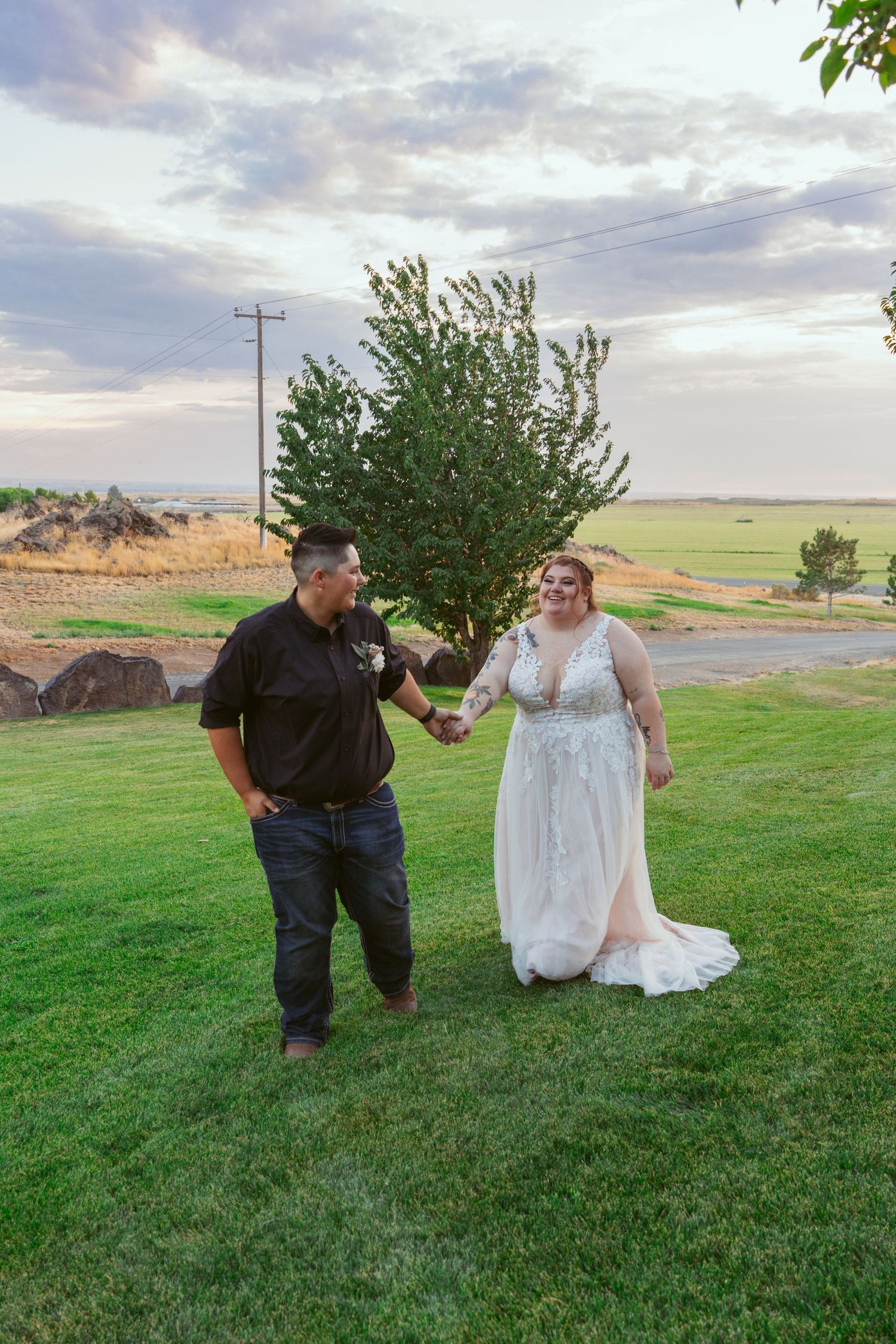 Wedding couple sharing playful moments on a grassy hill during their outdoor photoshoot.