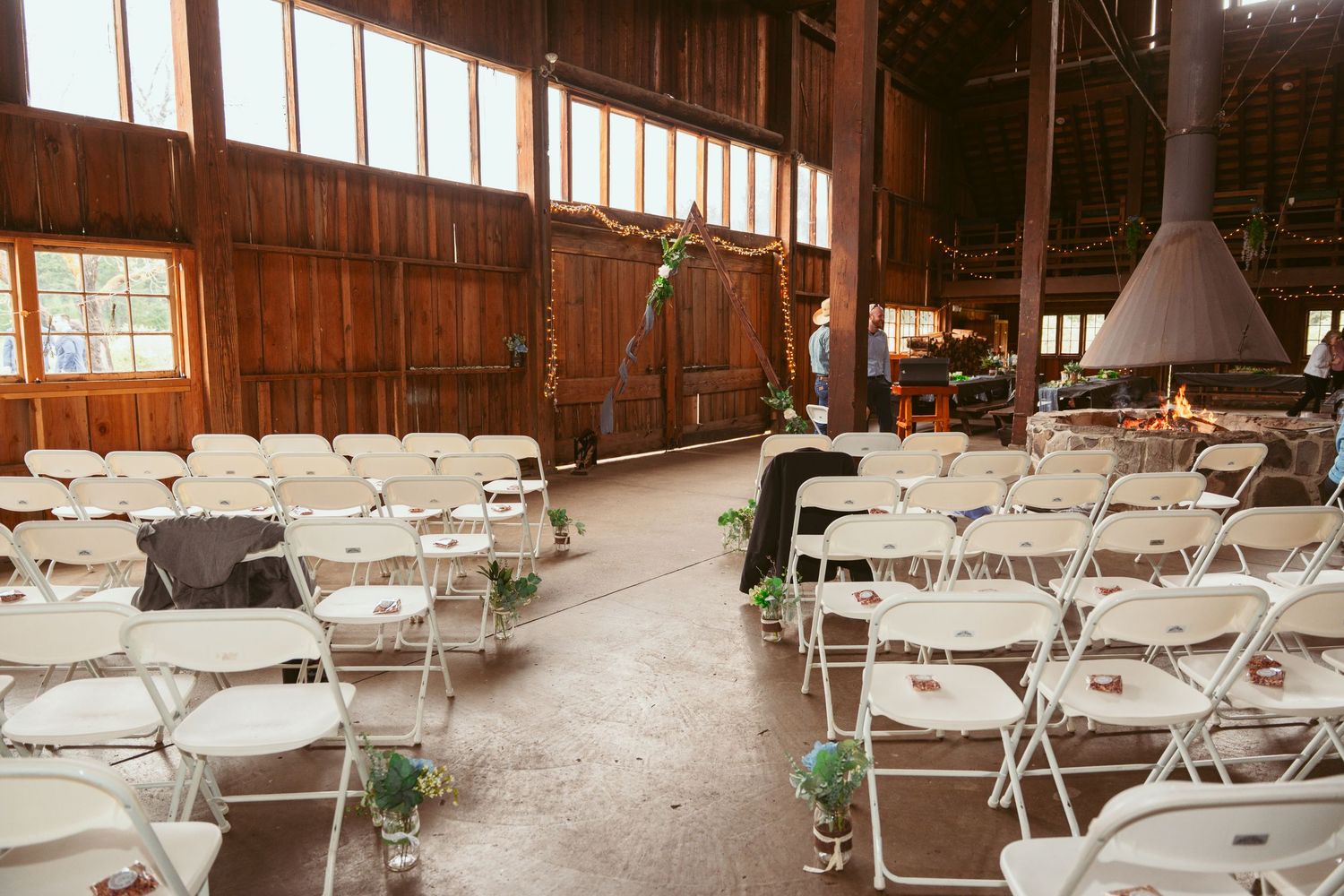 Large reception hall set up with white folding chairs and tables in rows.