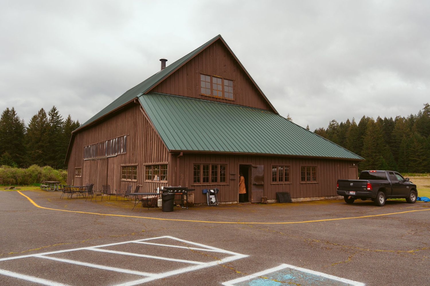 Exterior view of a large wooden barn wedding venue with parking area.