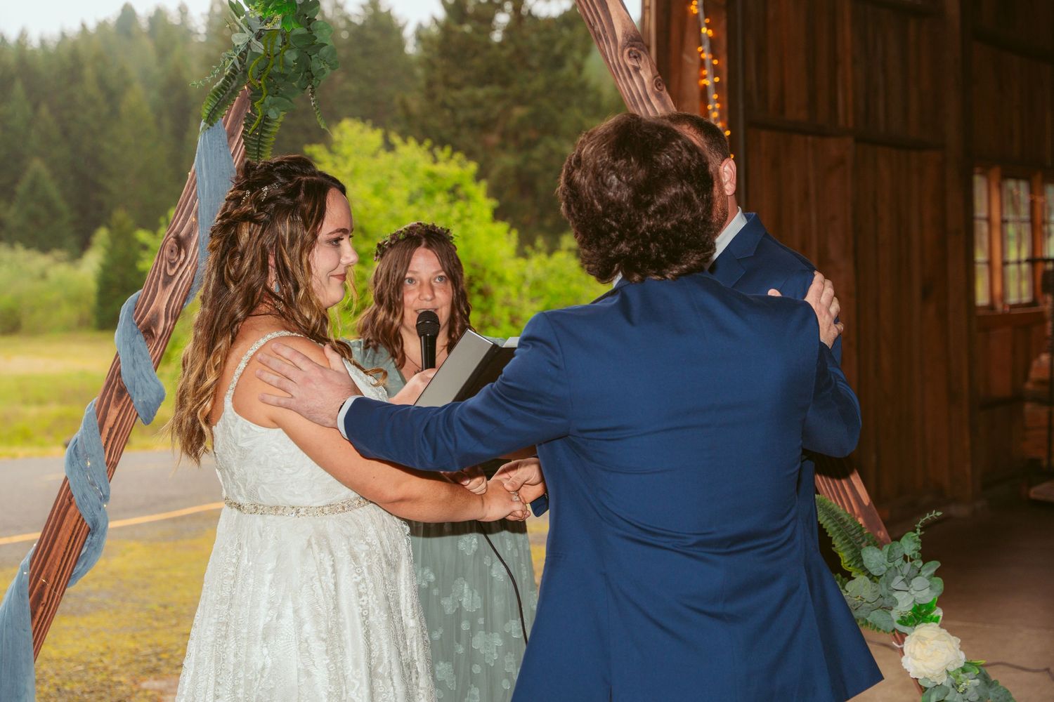 Intimate wedding moment captured in rustic barn setting with natural light streaming through windows.