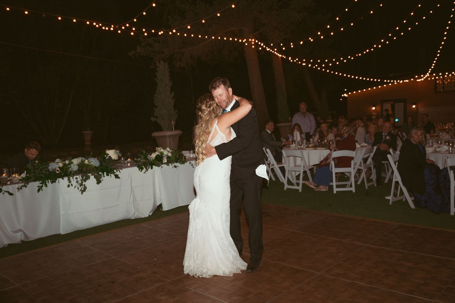 Wedding reception dance party under string lights with guests celebrating.
