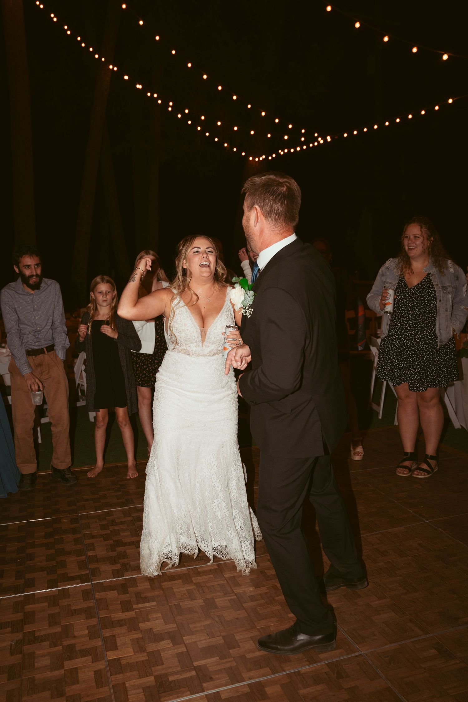Couples dancing together on a wooden dance floor at an evening wedding reception.