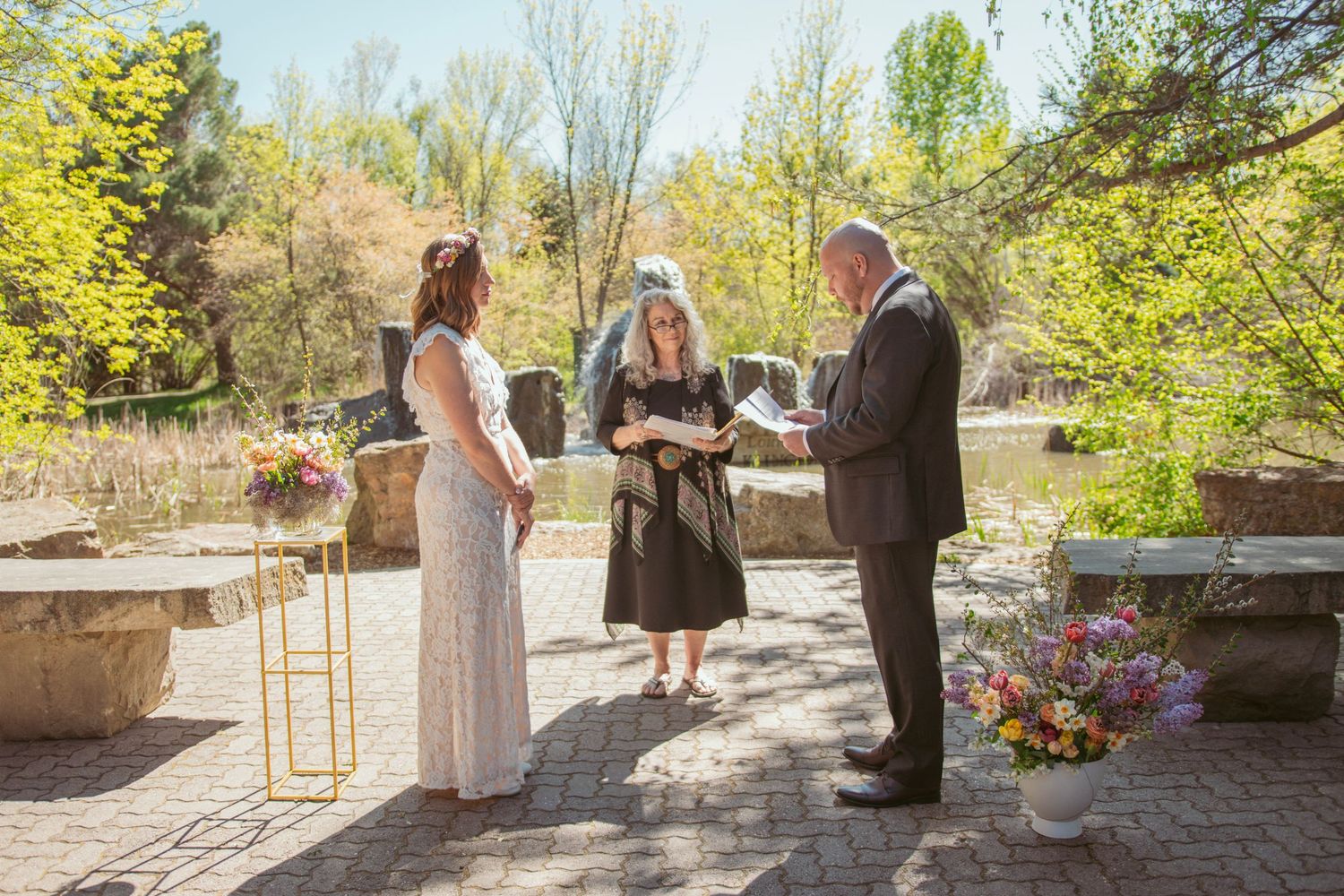 Outdoor wedding ceremony setup with wooden chairs and natural greenery in the background.