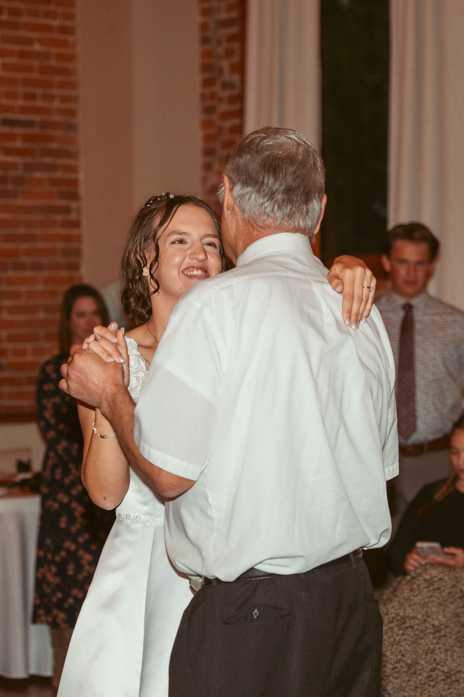 A joyful dance moment during a wedding reception with exposed brick walls and elegant table settings.