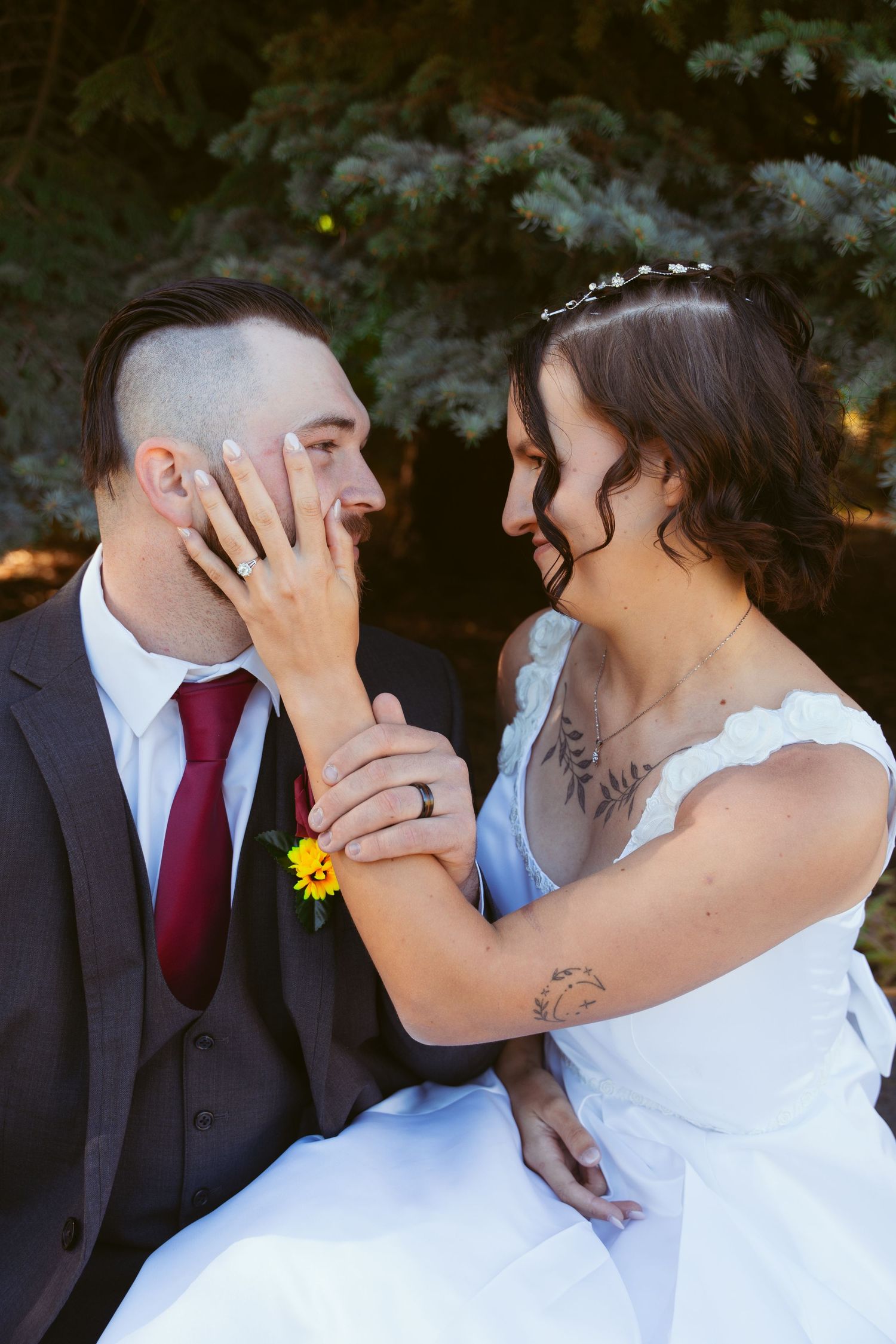 A tender moment between newlyweds as they share a loving touch outdoors.