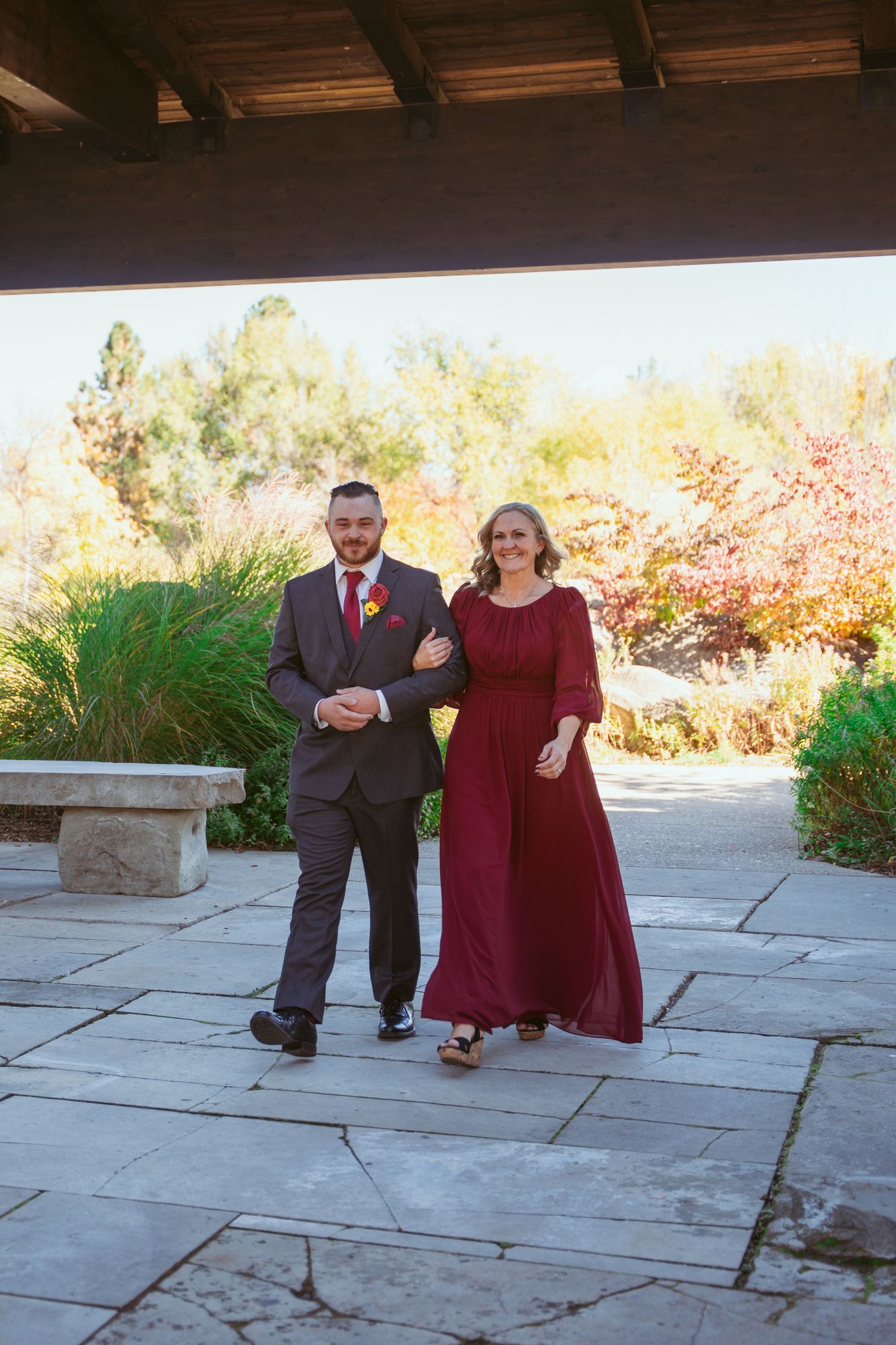 A couple in formal attire poses together on stone pavement during an outdoor wedding photo session.