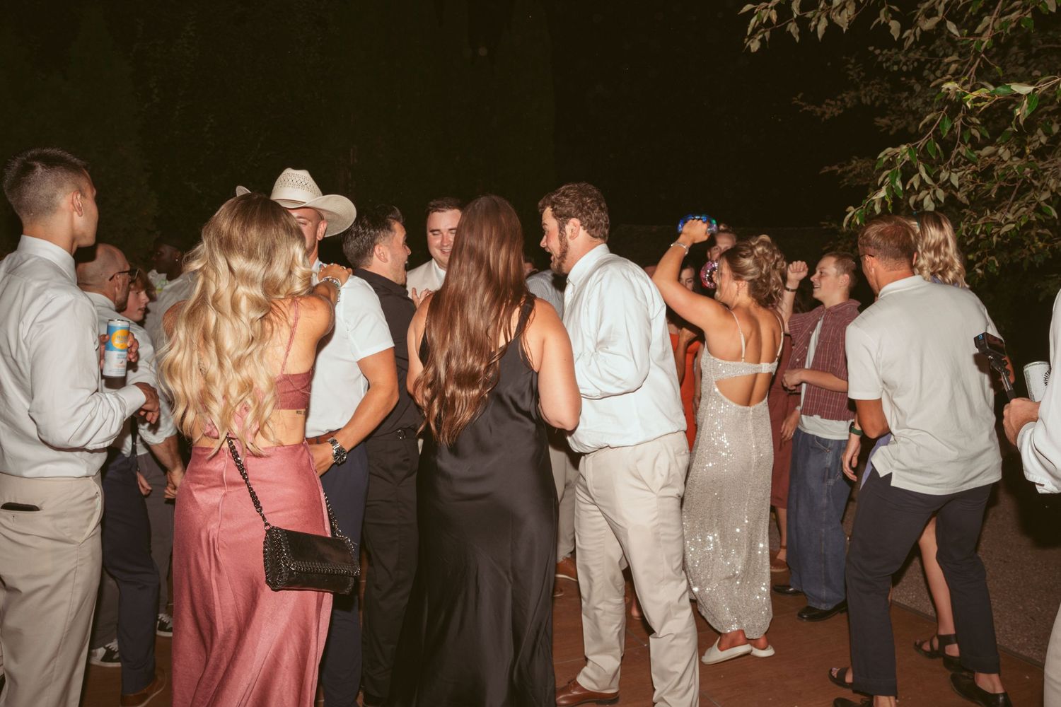 Wedding guests mingling and socializing at outdoor evening celebration.