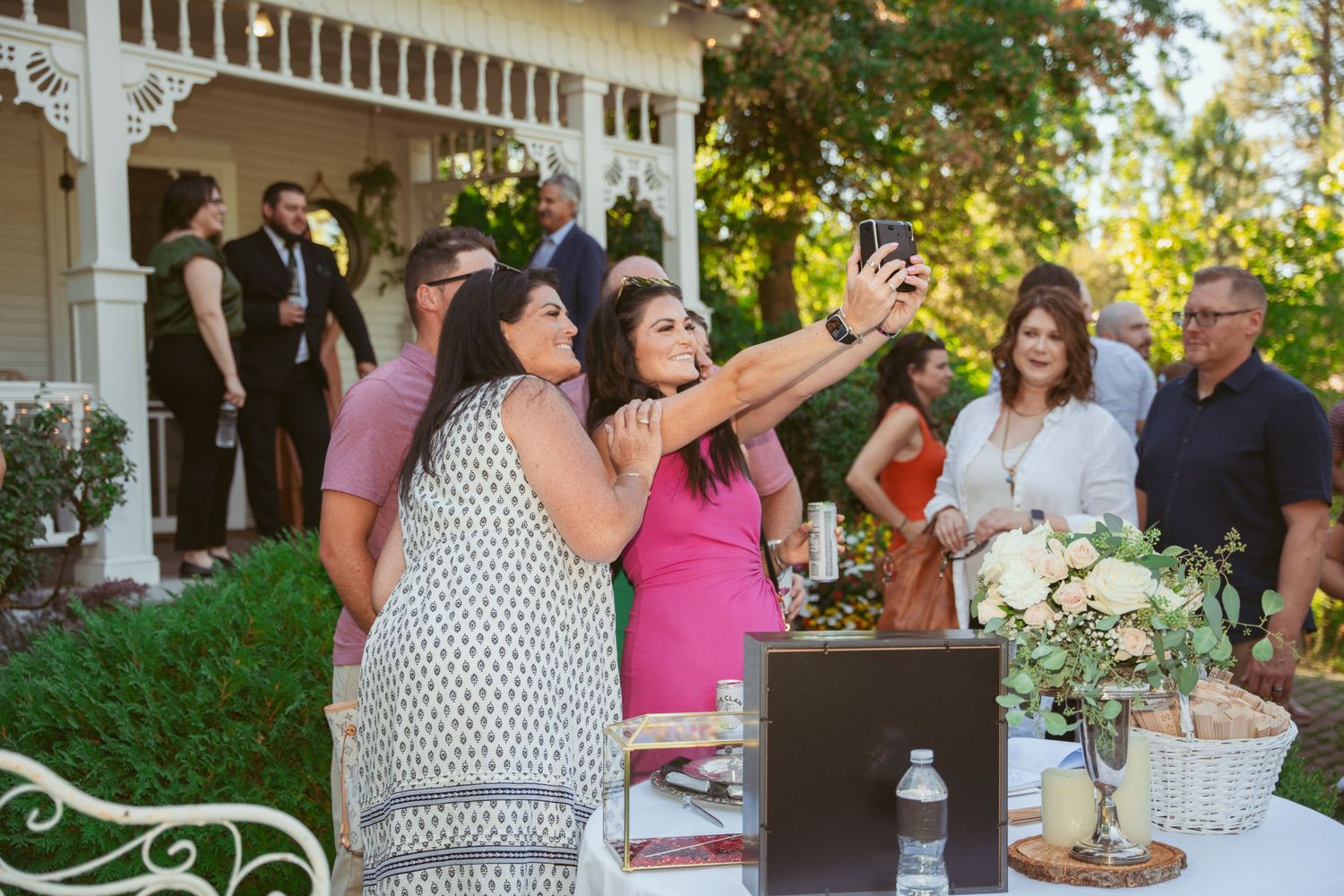 Wedding guests gather on an outdoor patio decorated with string lights and greenery during a summer celebration.
