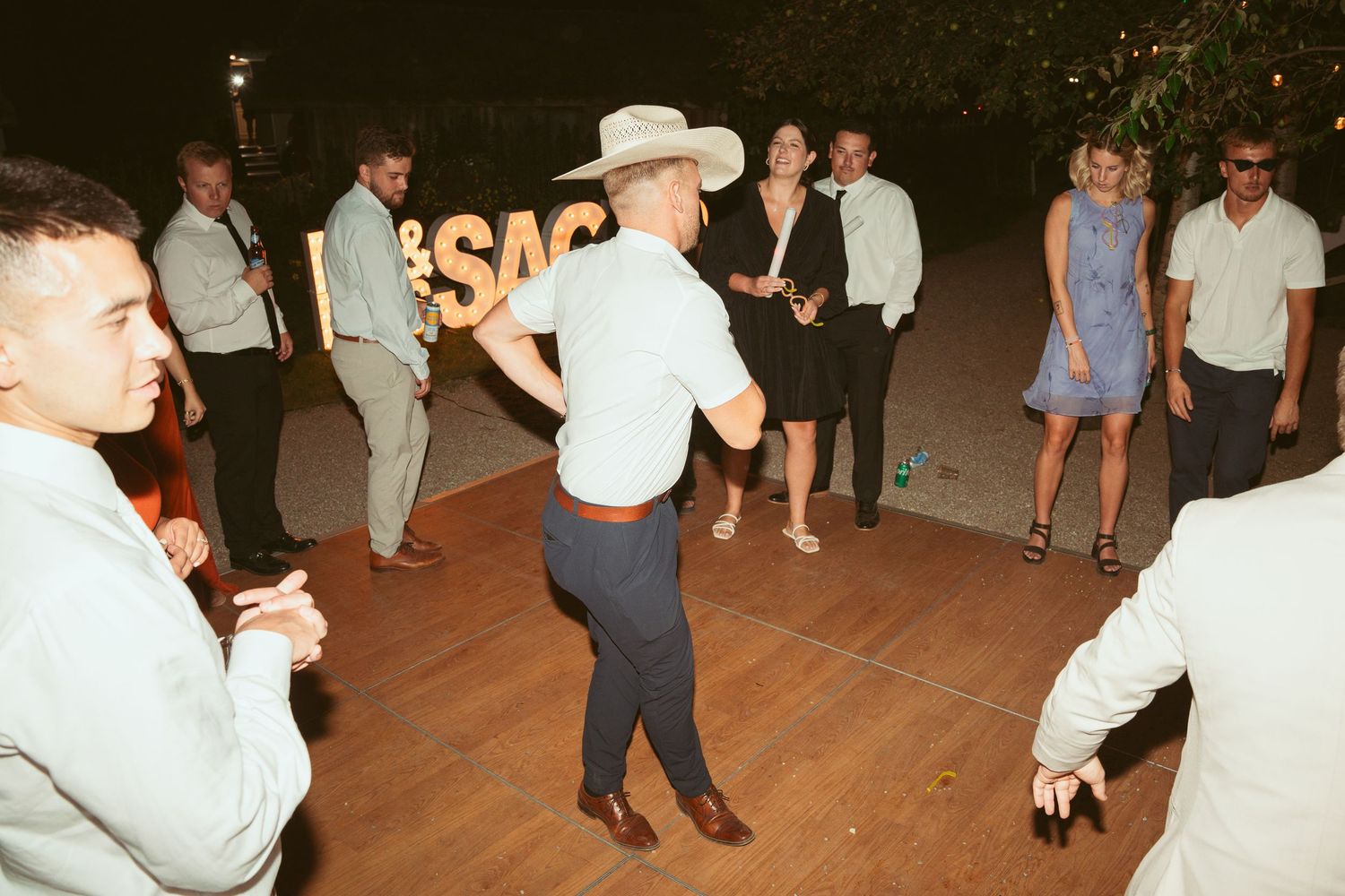 People dancing and mingling on an outdoor dance floor at a wedding reception.