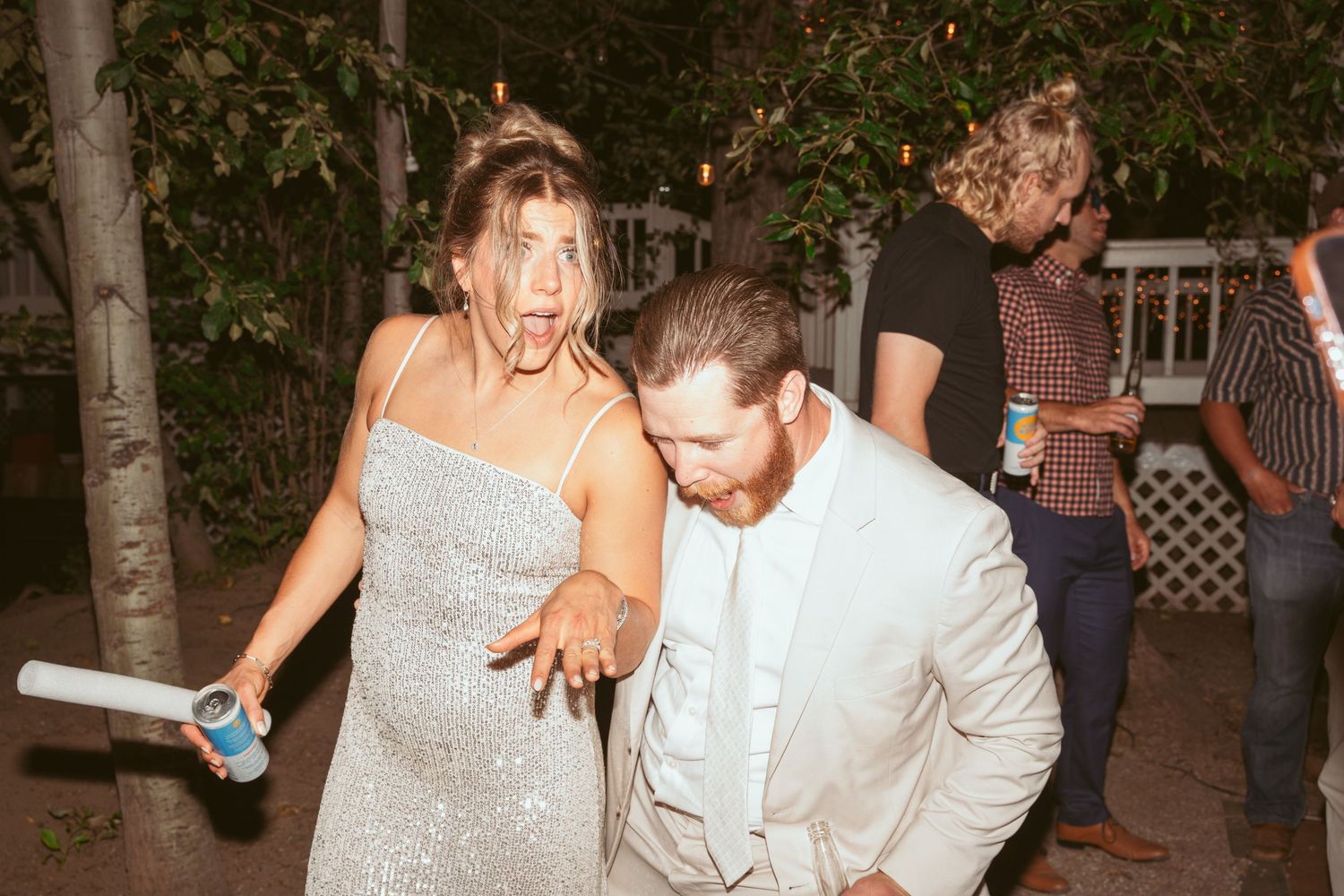 Wedding guests dancing and laughing together at an outdoor evening reception celebration.