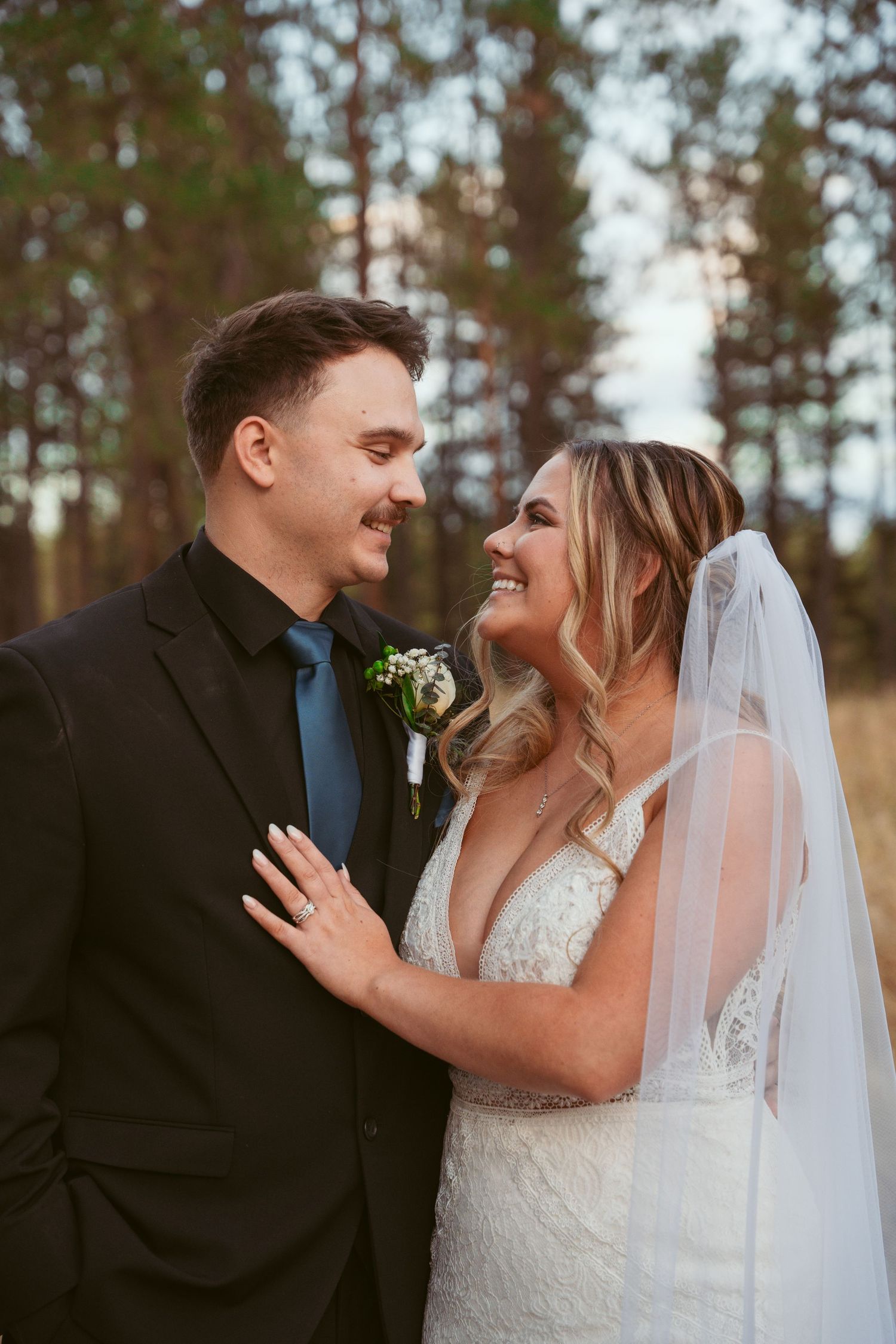 Intimate wedding portrait of a couple sharing a romantic moment against a backdrop of pine trees.