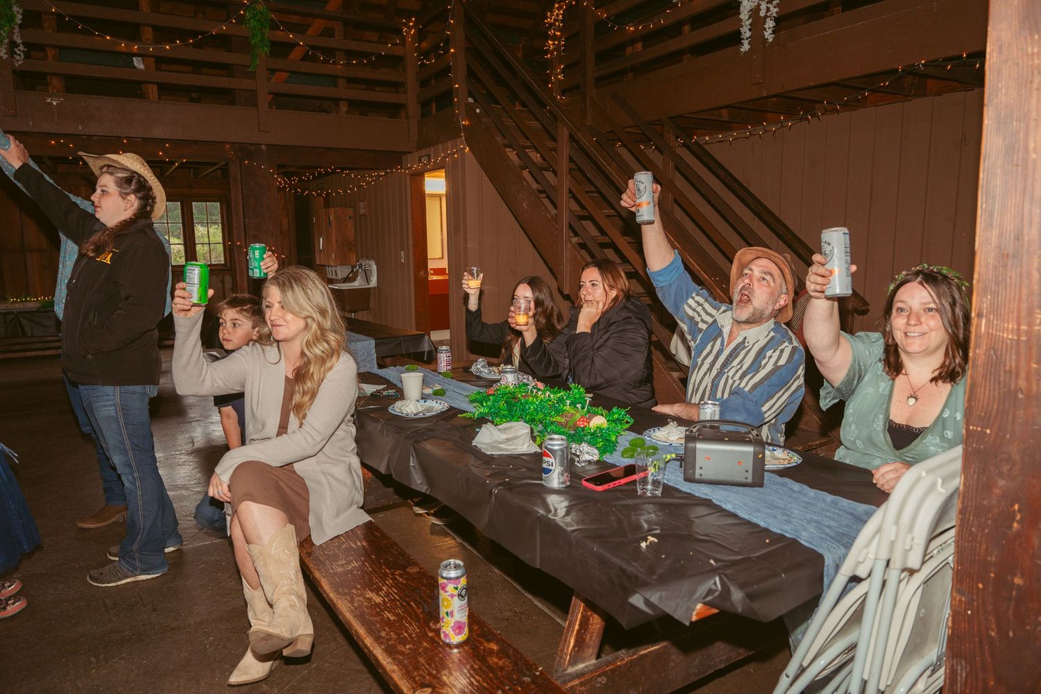 Party guests enjoying festivities at tables inside a decorated barn venue.