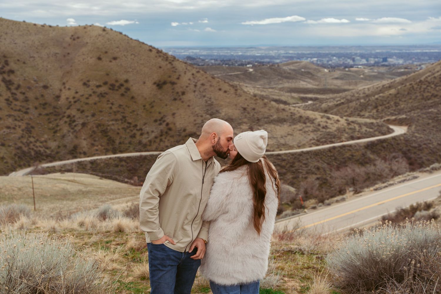 Scenic mountain landscape with a couple sharing a romantic moment on a winding trail.