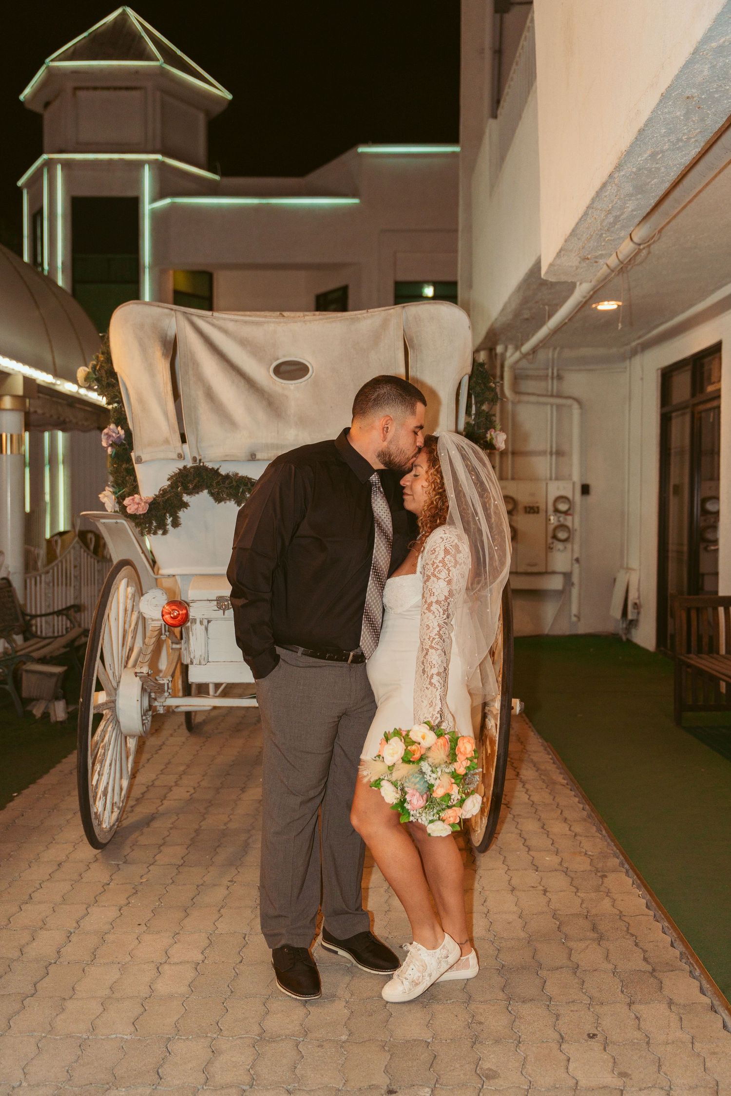 Couple dancing near an illuminated white carriage display at an indoor venue.