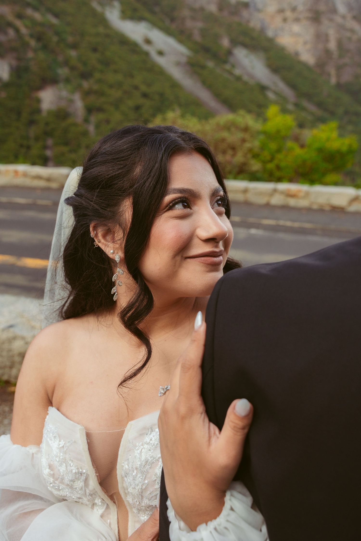 Close-up profile shots of a bride in a detailed lace wedding gown with mountains in the background.