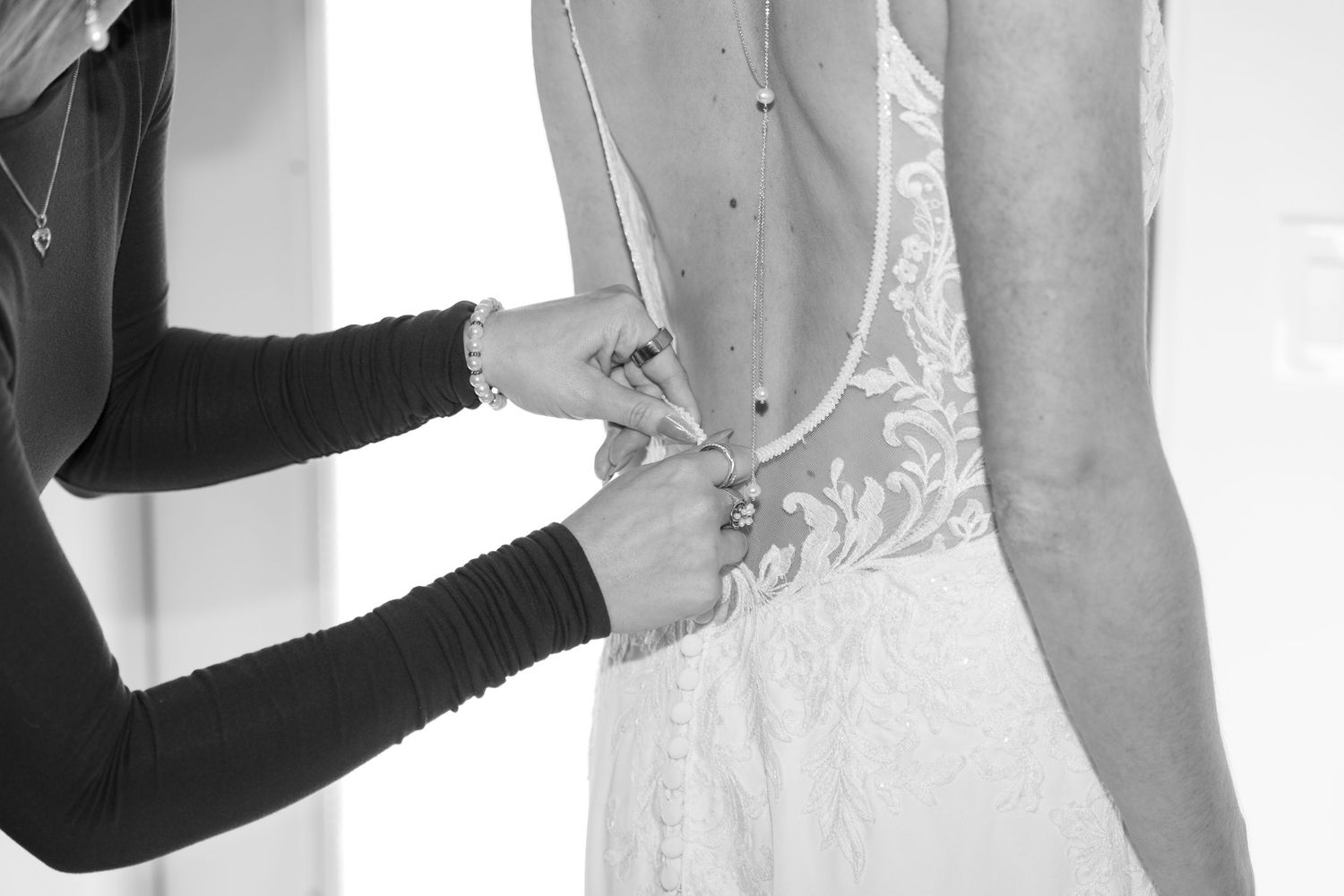 Close-up view of intricate lace details and buttons on the back of a white wedding dress.