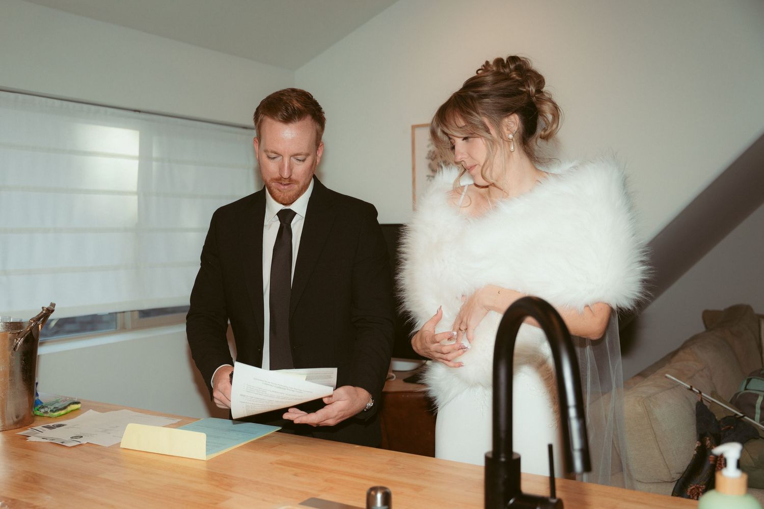 Wedding party members reviewing documents at a kitchen counter.