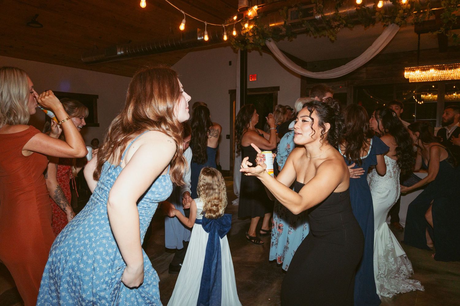 People dancing and celebrating at an indoor reception with warm ambient lighting.
