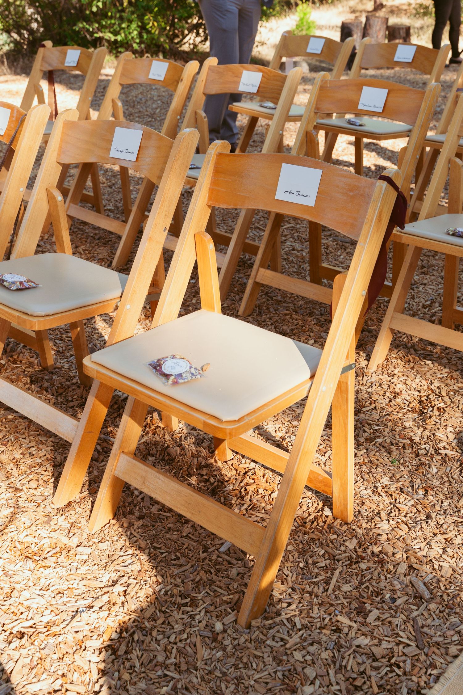 Rows of wooden folding chairs set up for outdoor wedding ceremony.