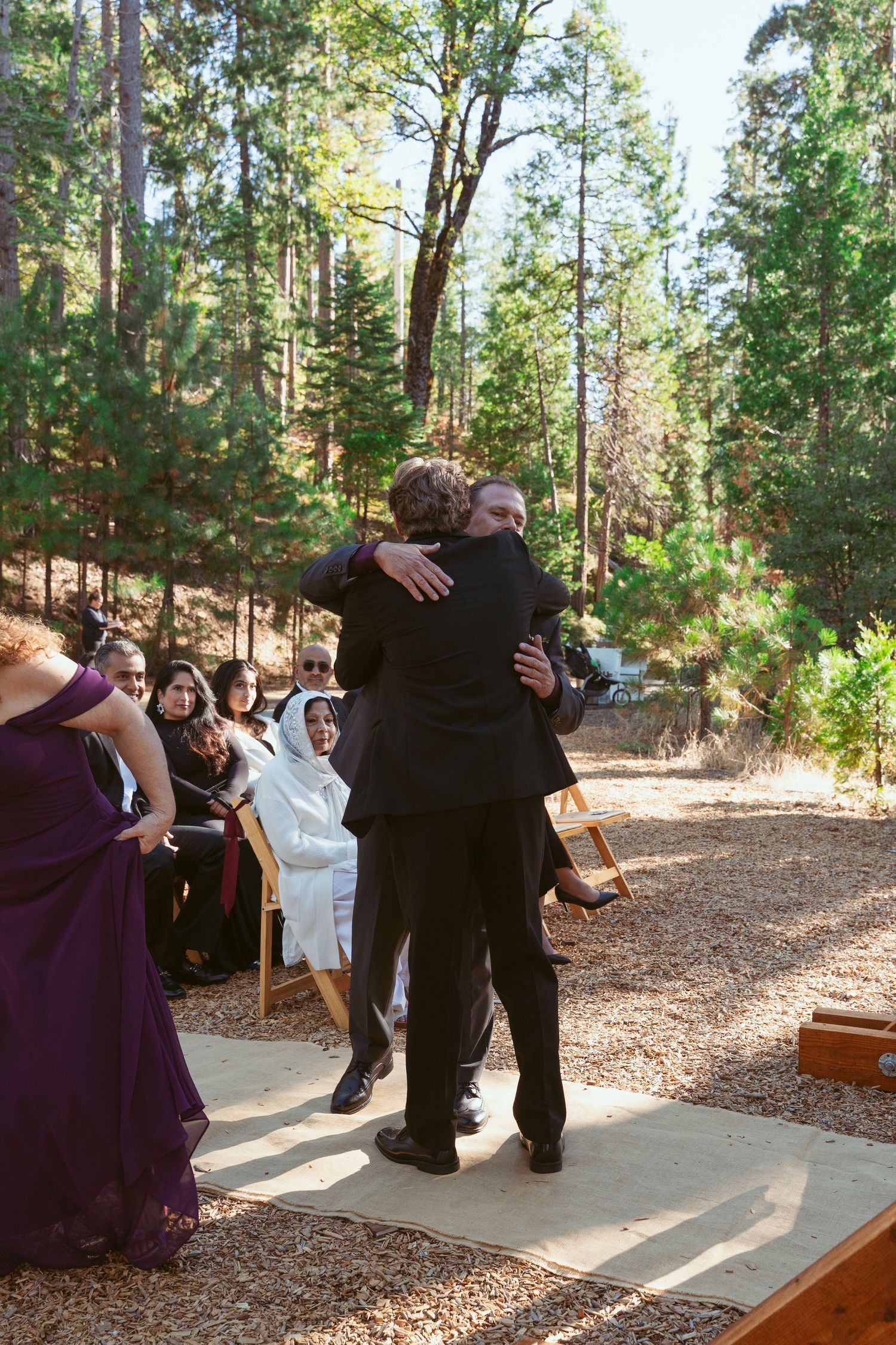 Wedding celebration moments captured on an outdoor stone pathway with forest backdrop.