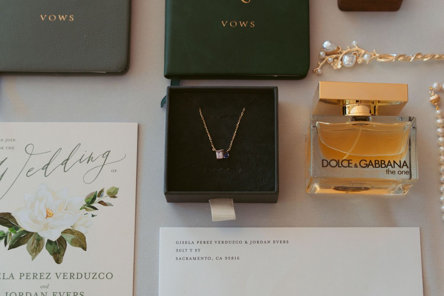 Wedding invitation suite with jewelry box and perfume bottle arranged on a flat surface.