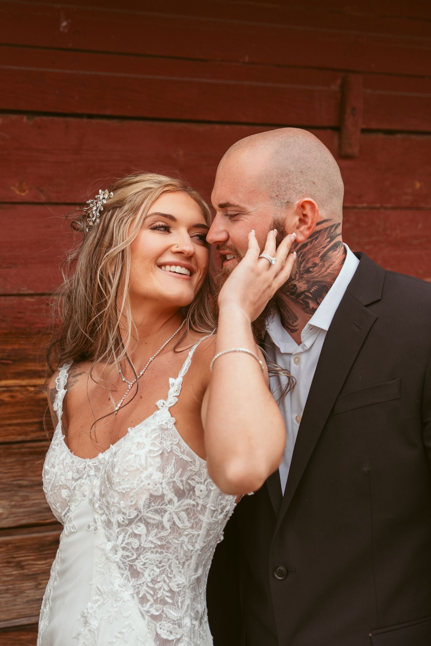 A romantic moment between newlyweds against a rustic red barn backdrop.
