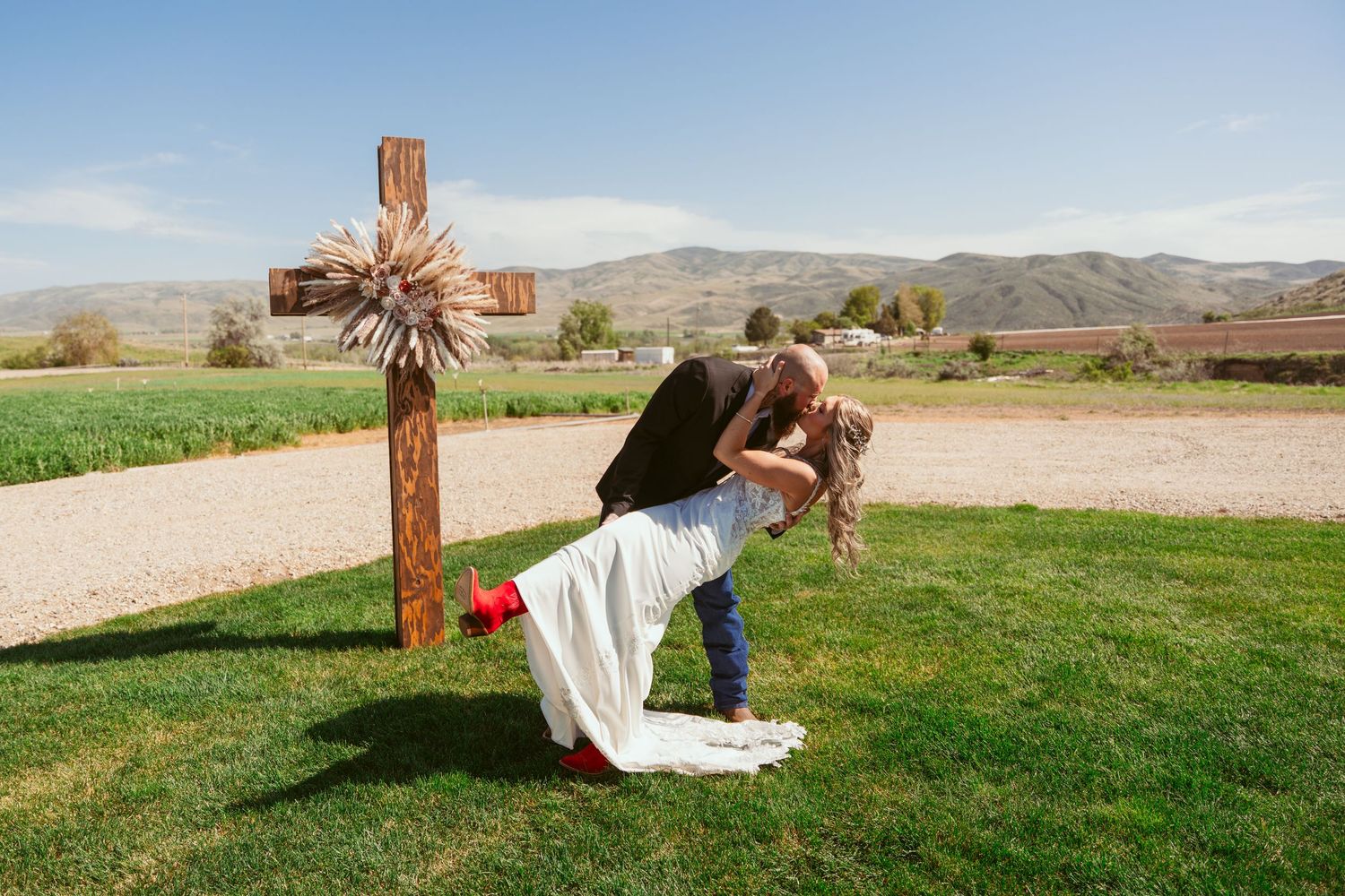 Panoramic view of a rustic outdoor wedding venue with wooden cross and mountain backdrop.