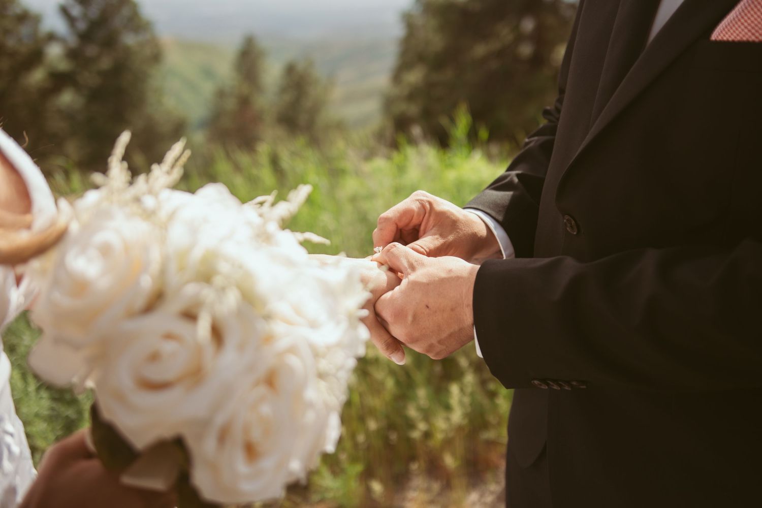 White wedding bouquet being held during an outdoor ceremony.