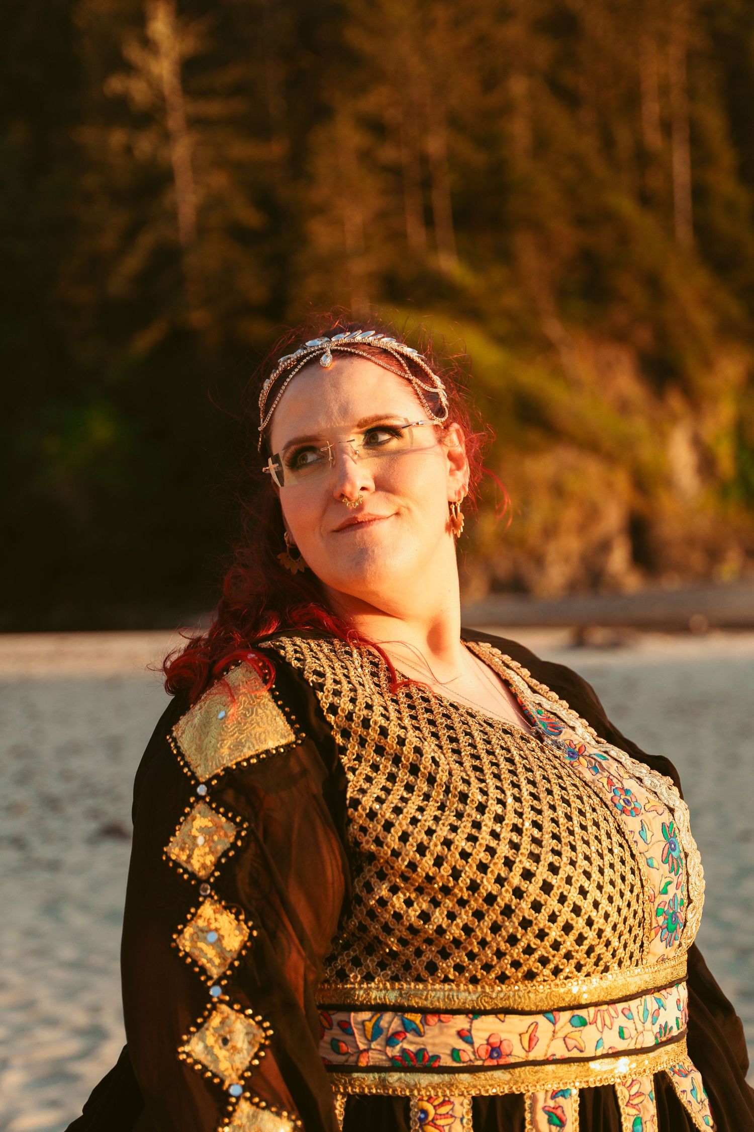 Person wearing an ornate gold and black patterned dress smiling in warm sunset light.