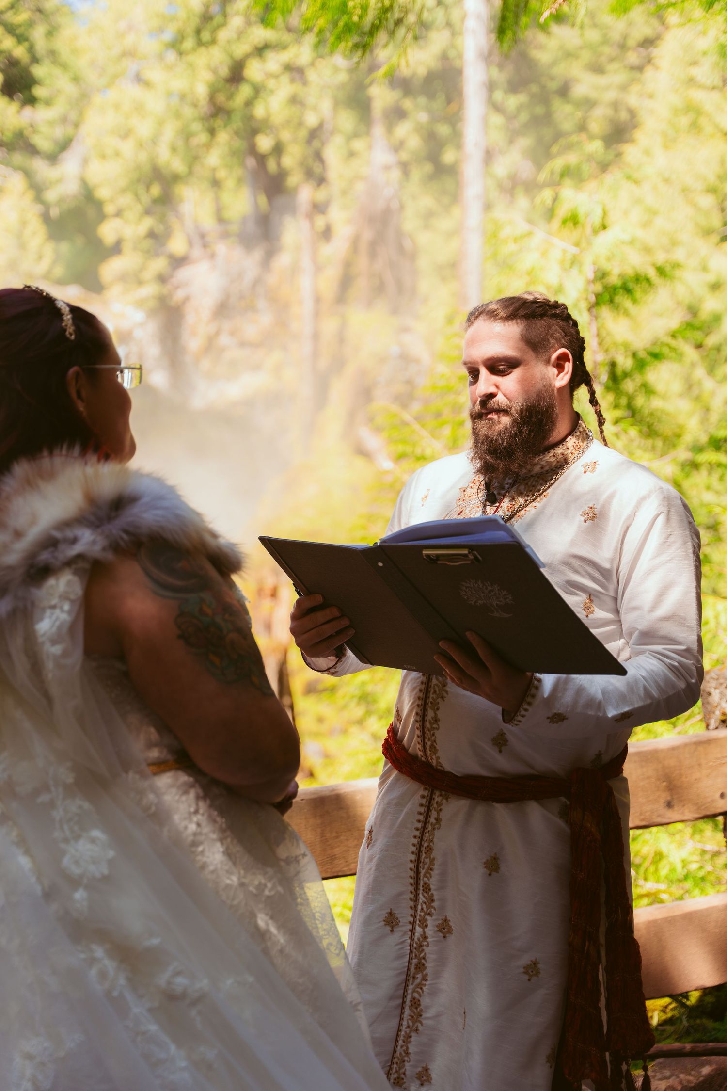 Couple dancing together in a romantic outdoor forest setting with natural sunlight filtering through trees.