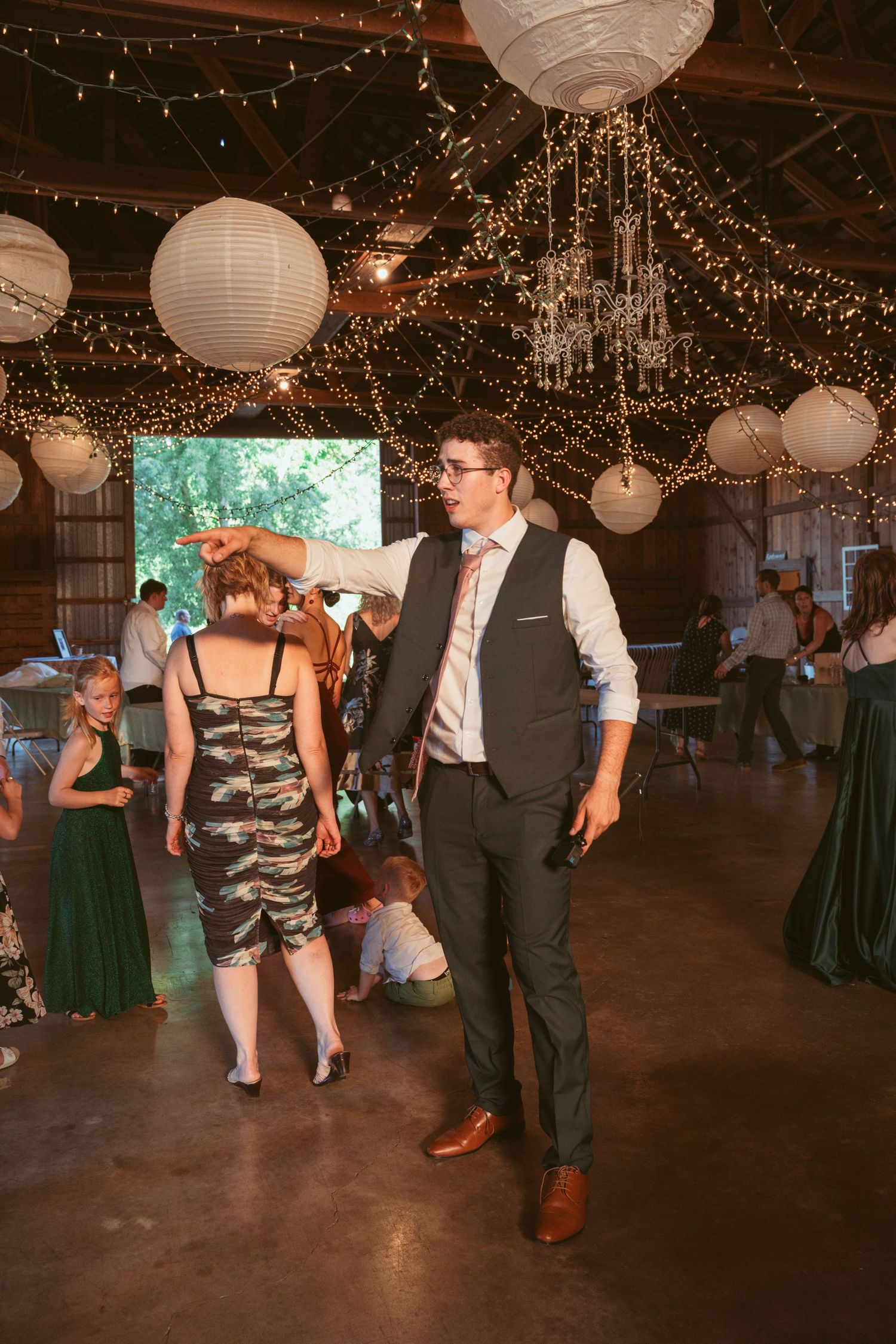 Couples swing dancing on a rustic dance floor under glowing string lights and paper lanterns.