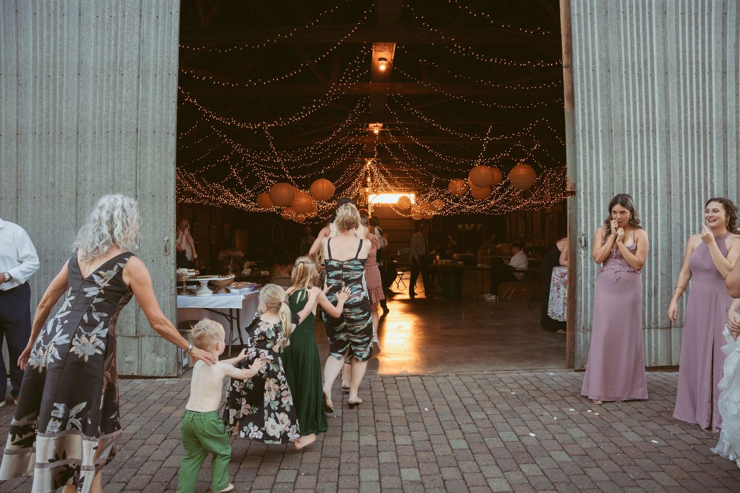 Guests perform a choreographed dance routine at a rustic barn wedding reception.