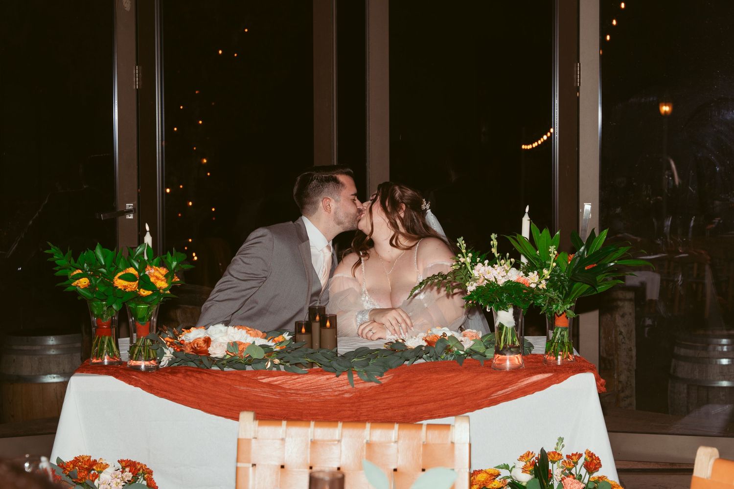 Wedding reception tables decorated with floral centerpieces and candles in an elegant indoor venue.