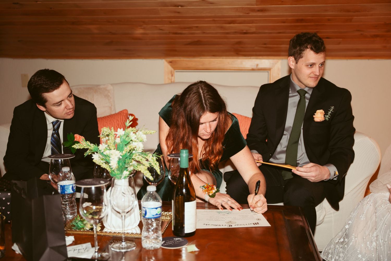 Wedding document signing ceremony at indoor reception with wooden decor.