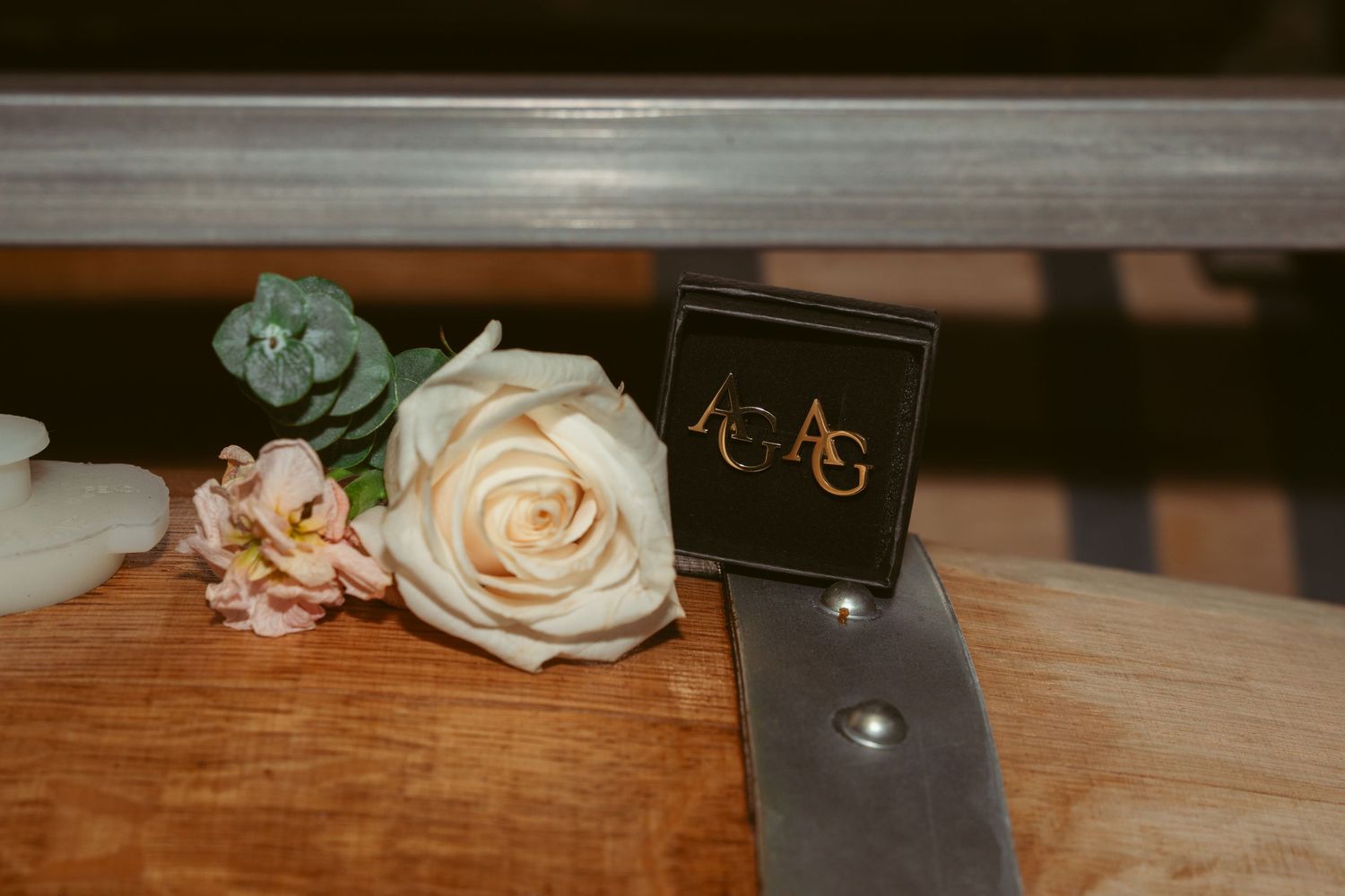 White and peach roses next to a small black ring box on wooden surface.