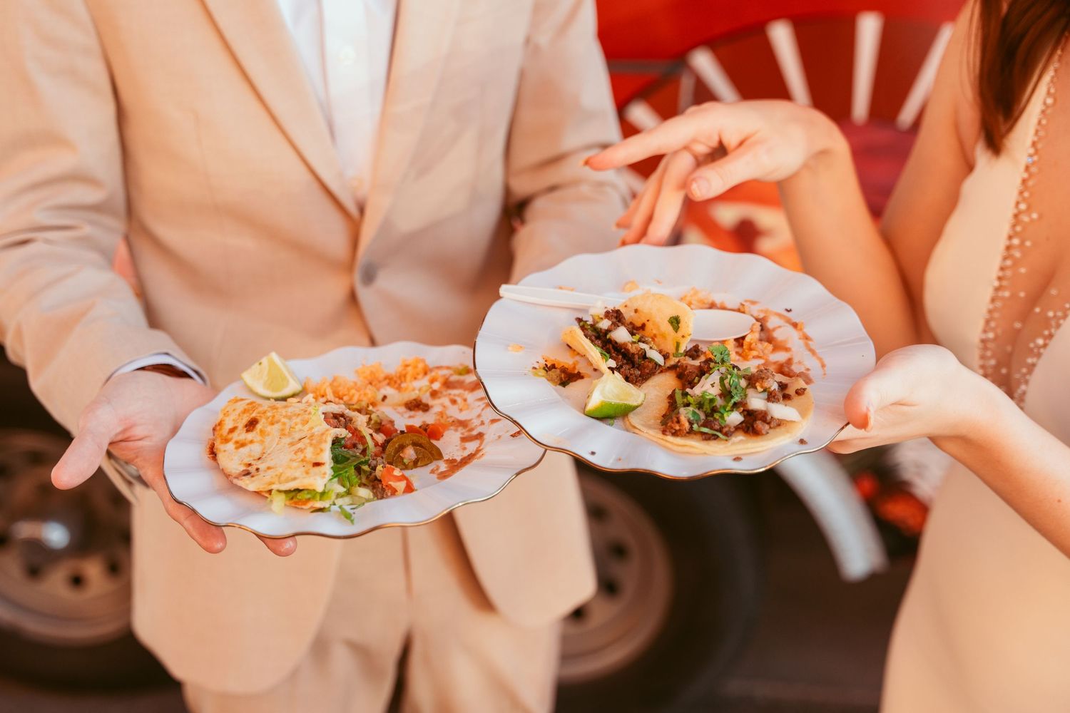 Wedding reception guests enjoying plates of delicious catered food at elegant dining tables.