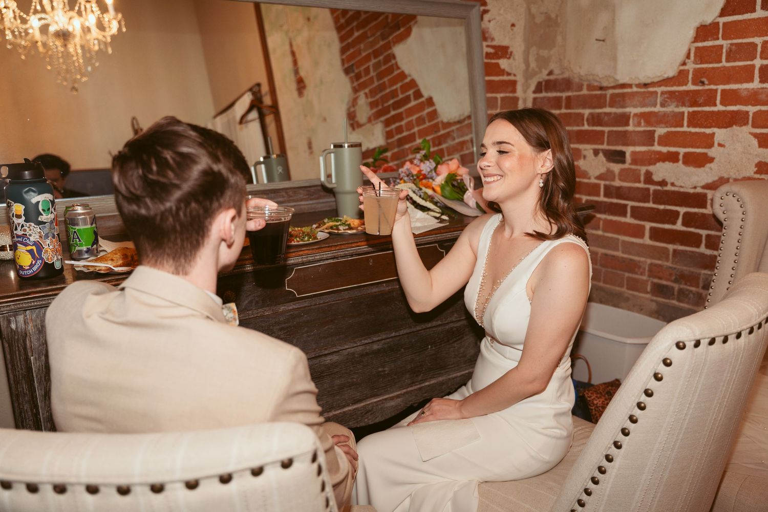Wedding celebration candid moments captured in rustic brick venue with chandelier lighting.