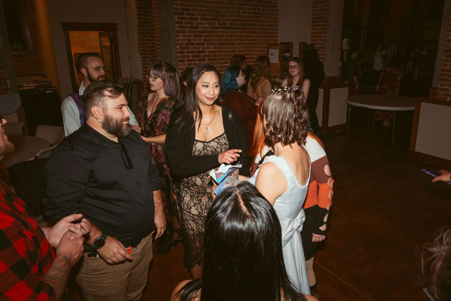 Party guests mingling and socializing on a dance floor in an industrial-style venue.