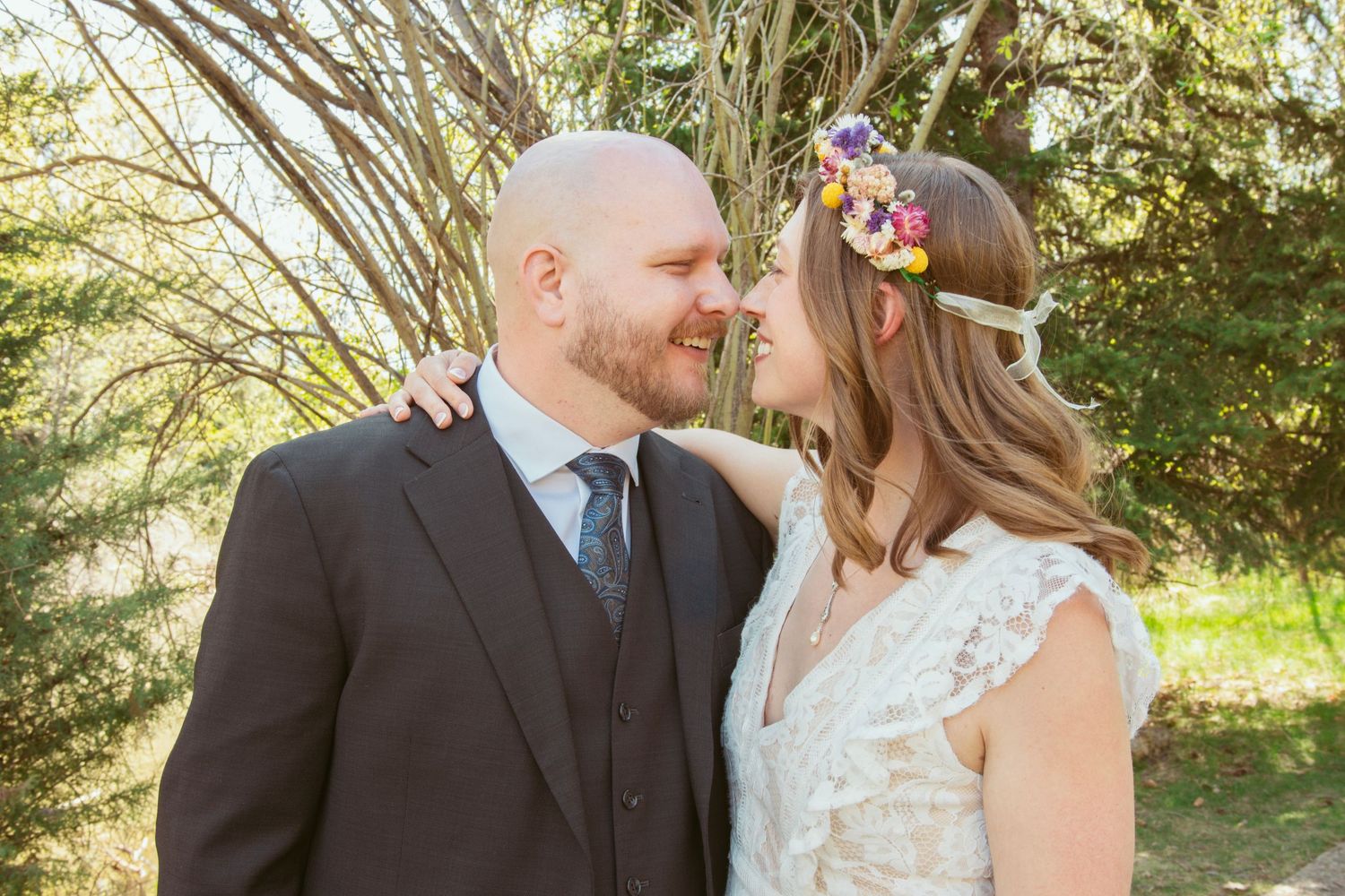 Romantic wedding couple embracing during their outdoor spring ceremony.