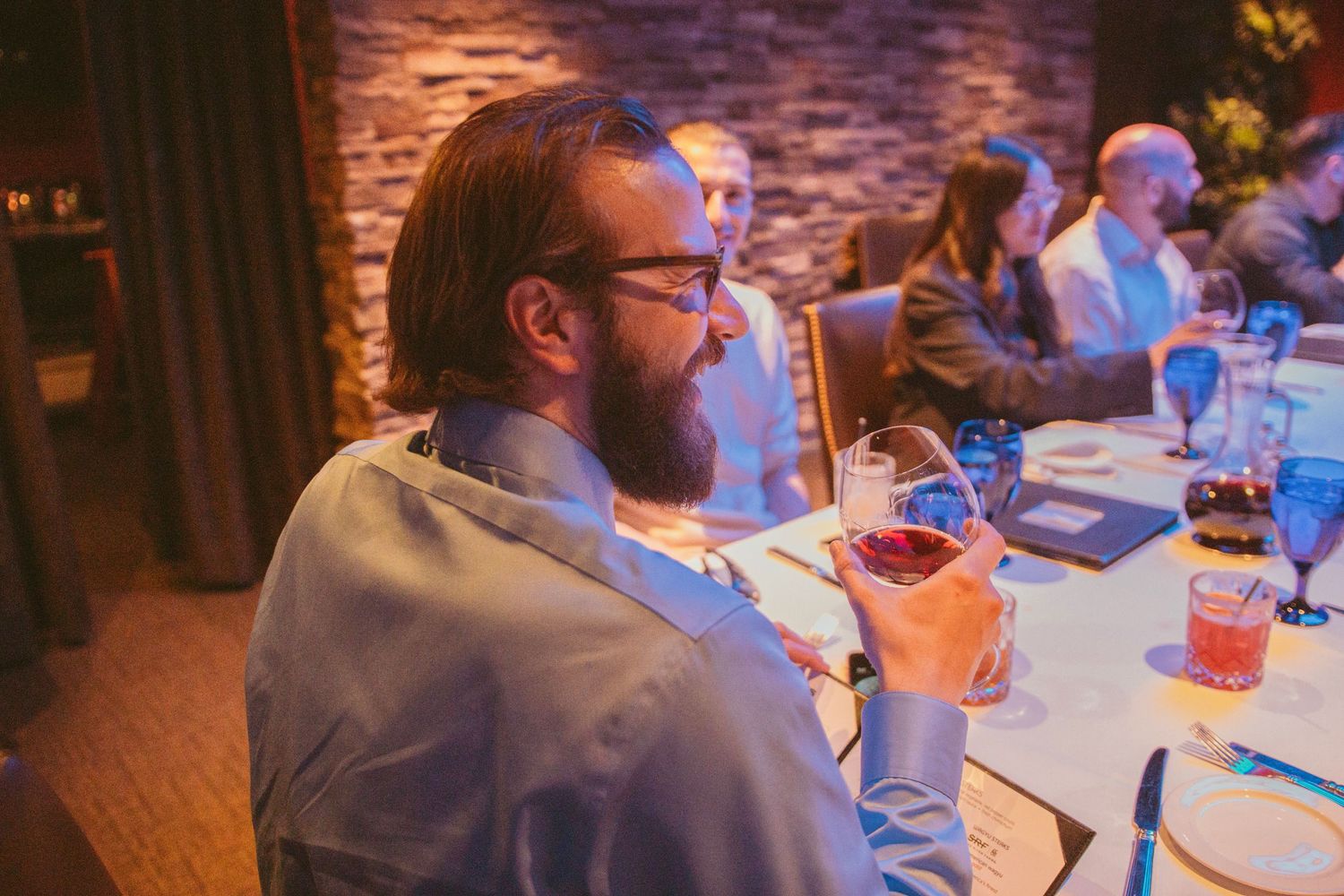 Wedding guests enjoying dinner at tables with ambient lighting.