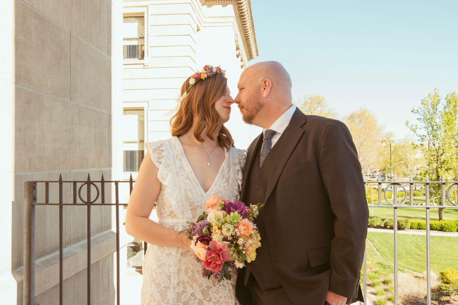 Romantic outdoor wedding portraits with sunlit columns and spring scenery.