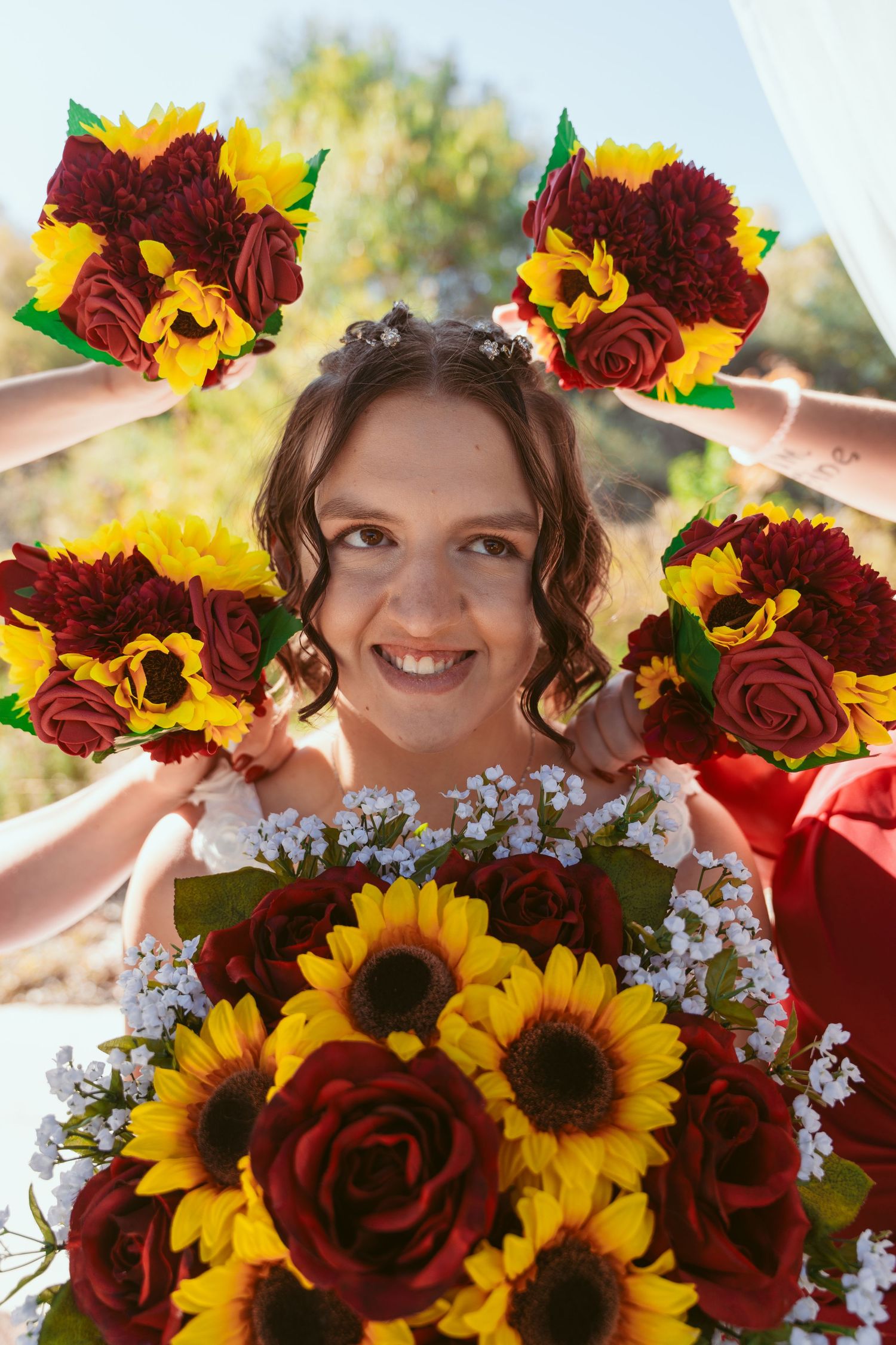 Wedding bouquet featuring vibrant sunflowers and deep red roses with white accent flowers.