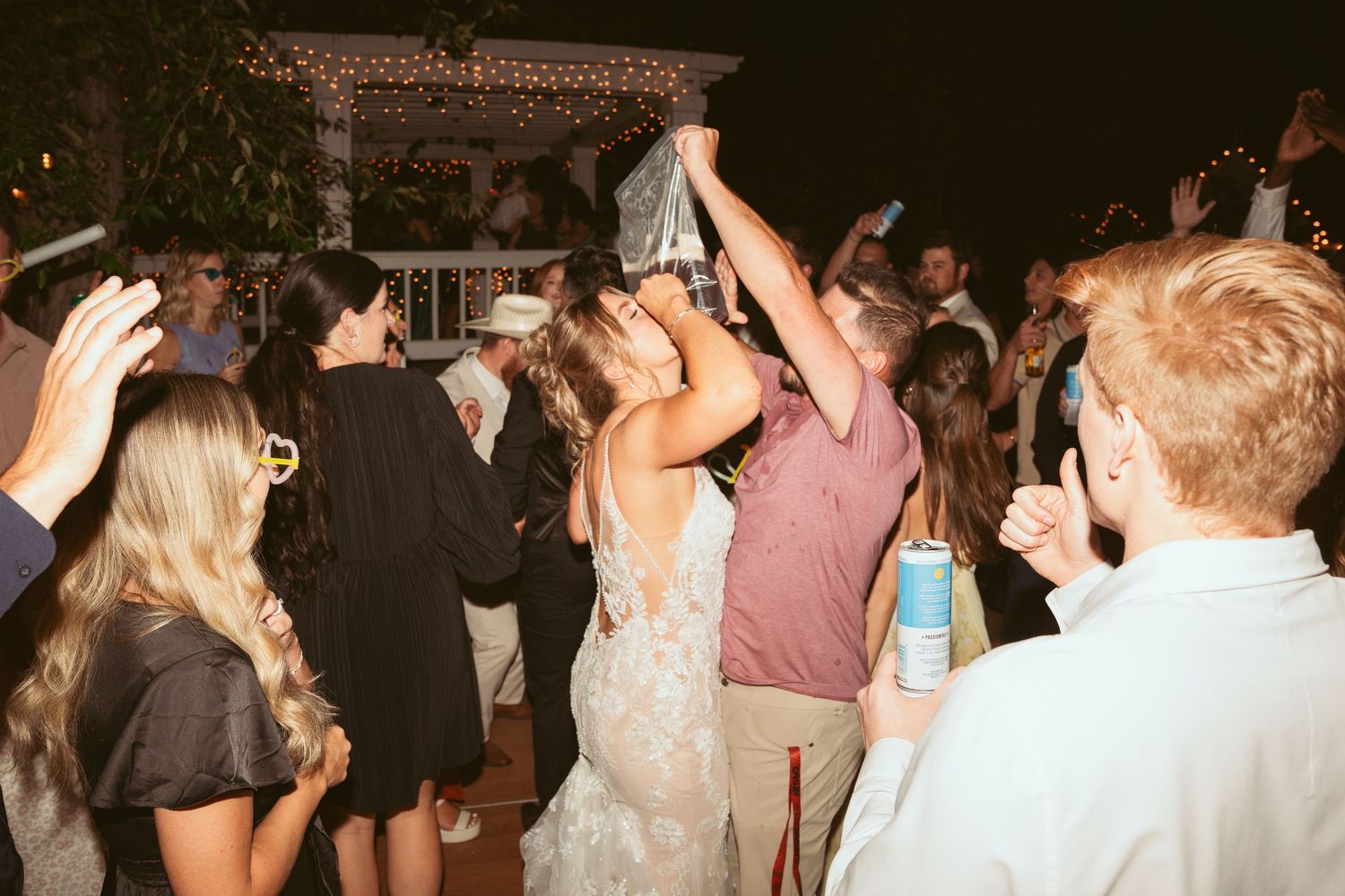 Wedding guests dancing with raised arms during nighttime celebration.