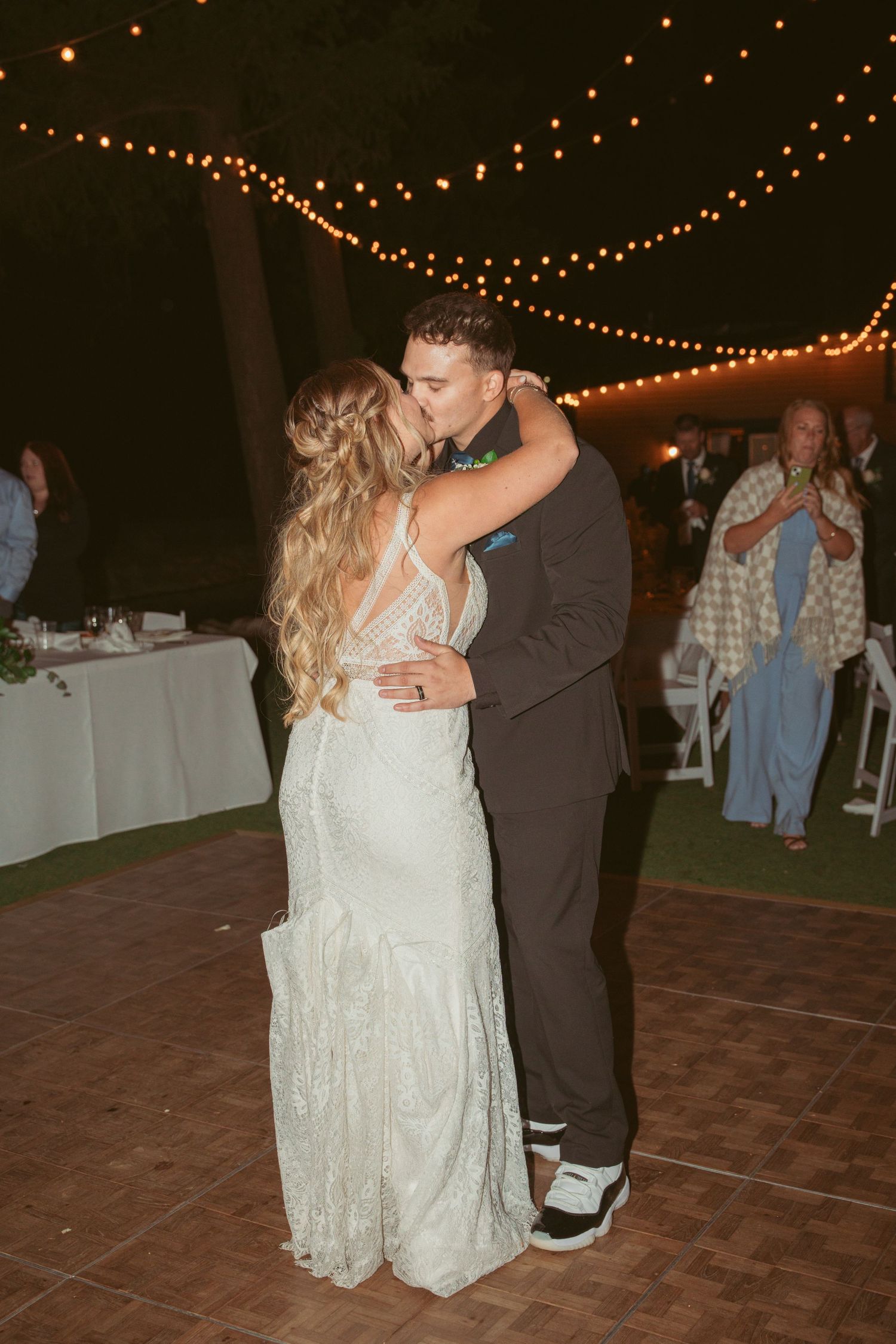 A couple sharing a romantic slow dance moment at an outdoor evening wedding reception.