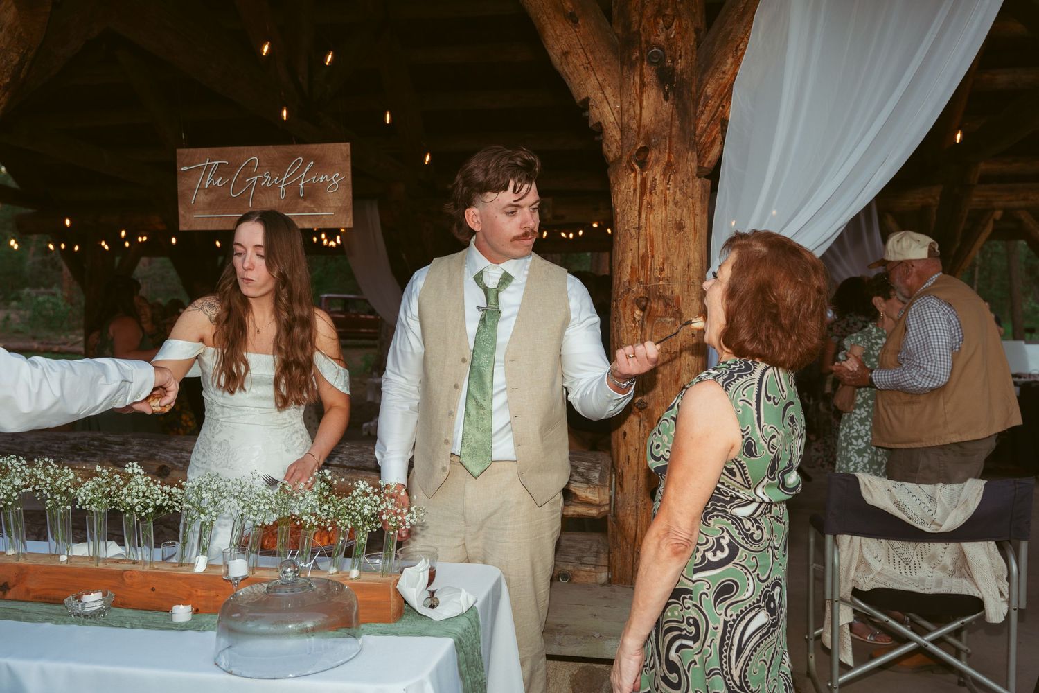 Wedding reception in a rustic barn setting with decorative lighting and wooden architectural details.