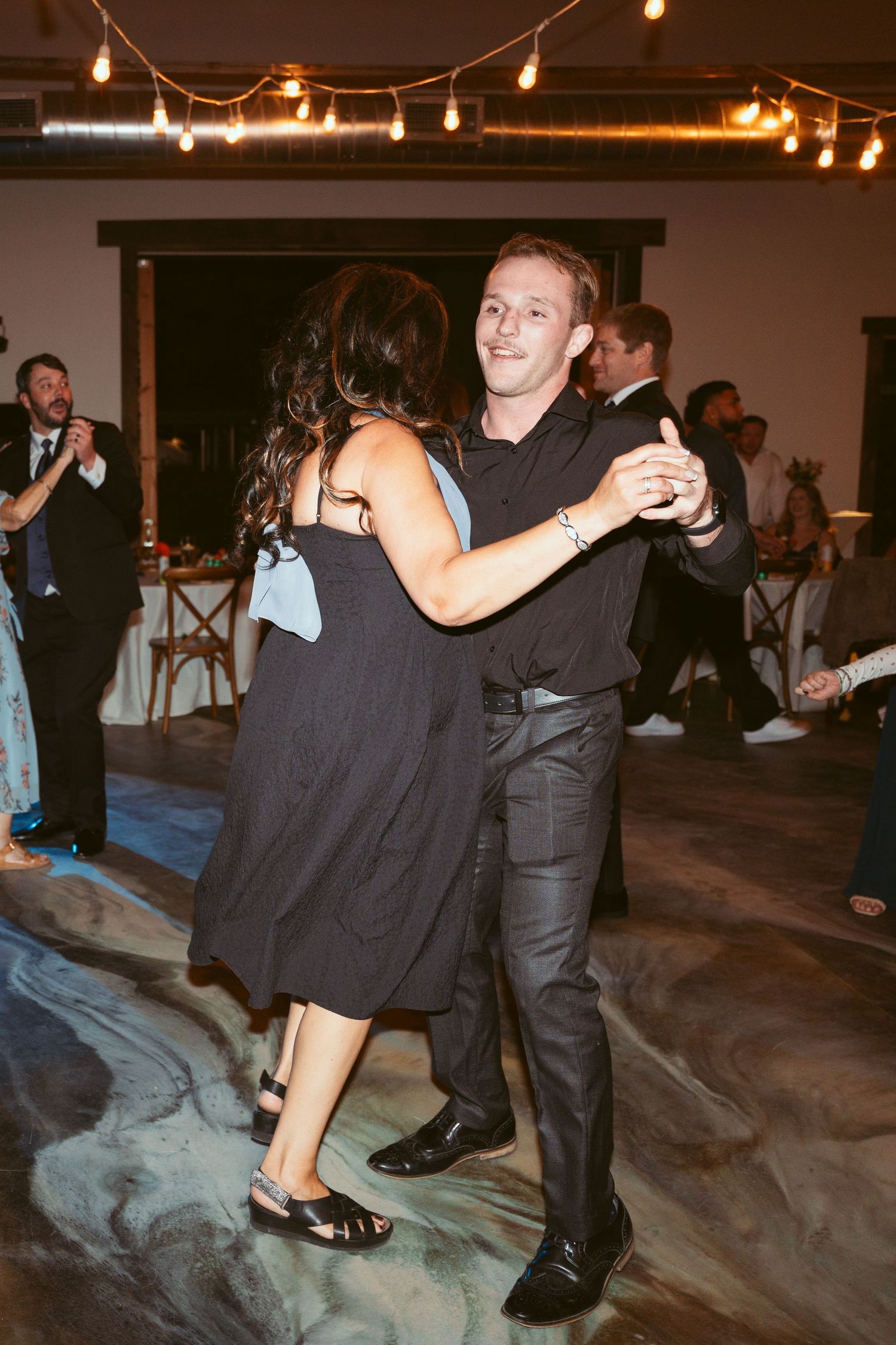 Couples dancing and twirling on a dark dance floor at an evening event.