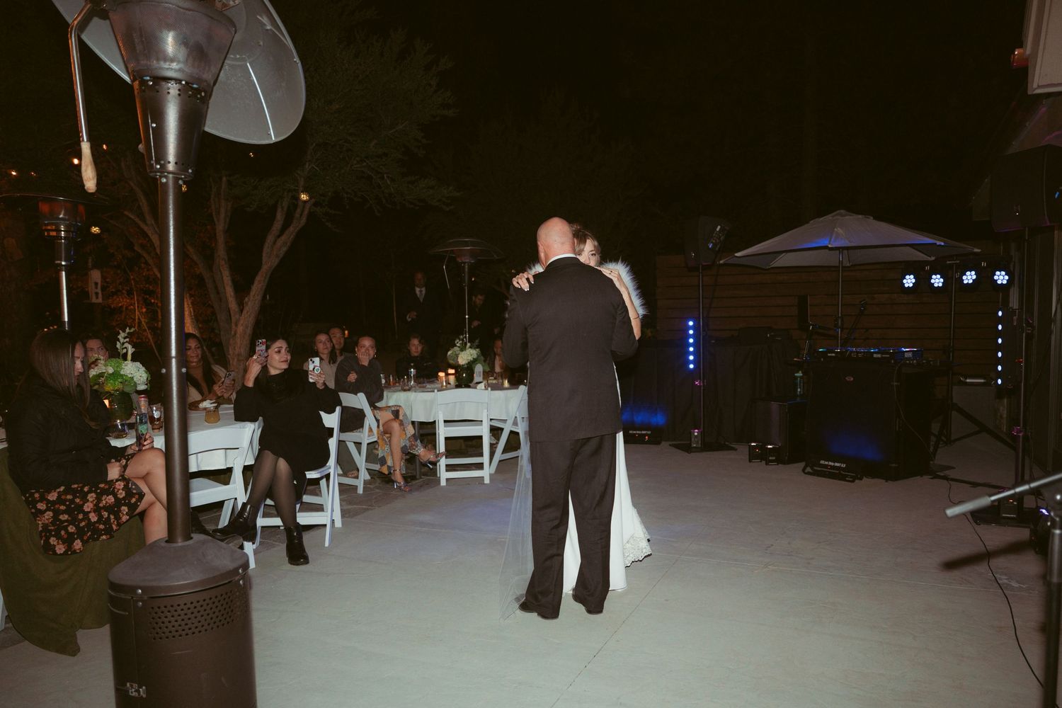 Wedding reception dance floor illuminated with blue lighting in outdoor nighttime setting.