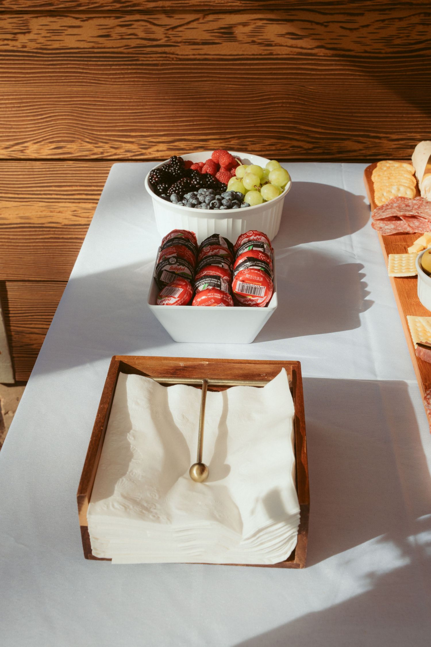 Wooden charcuterie boards with assorted snacks casting dramatic shadows on a rustic table.