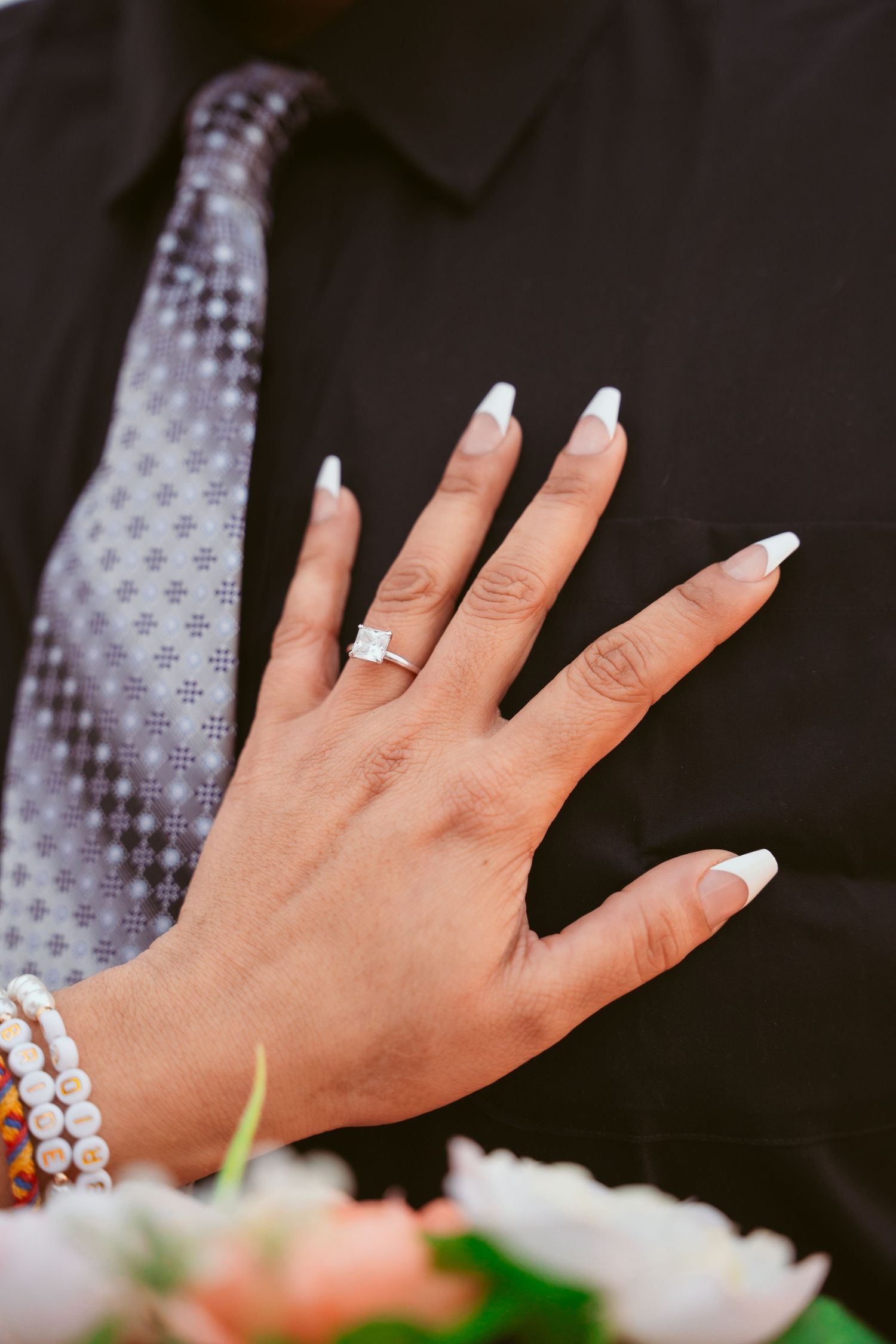Close-up of a wedding ring on a hand with white manicured nails.