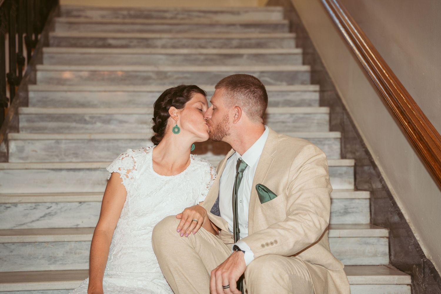 A couple shares intimate moments on marble stairs indoors.